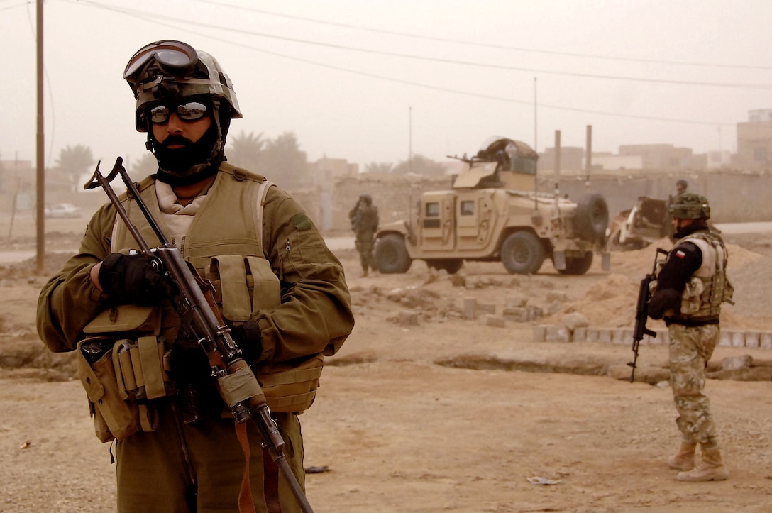 Polish army soldiers secure the area as Civil-Military Cooperation group members distribute supplies to Iraqi civilians in the city of Ad Diwaniyah, Iraq, Feb. 20, 2008. 