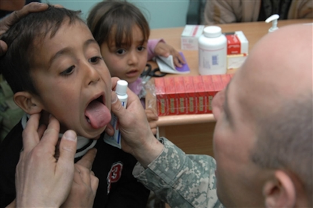 A young Iraqi boy opens wide for U.S. Army Maj. Michael Bimson and an Iraqi doctor as they examine the boy during a cooperative medical engagement at the Jayzeni Medical Clinic in the Diyala province of Iraq on Feb. 24, 2008.  Bimson is a brigade surgeon from the 2nd Squadron, 1st Cavalry Regiment.  