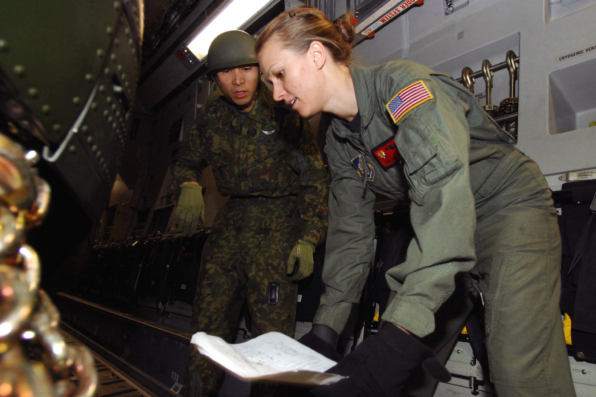 Senior Airman Lisa Long (right) and a Japan Ground Self Defense Force member load a JGSDF CH-47J Chinook onto a C-17 Globemaster III Feb. 23 at Yokota Air Base, Japan. The demonstration was conducted during the Pacific Global Air Mobility Seminar held Feb. 22 and 23. Sergeant Boehm is a loadmaster assigned to the 535th Airlift Squadron at Hickam Air Force Base, Hawaii. The C-17 is also assigned to the 535th Airlift Squadron. The CH-47J is assigned to the 1st Helicopter Brigade at JGSDF Camp Kisarazu in Kisarazu City, Chiba Prefecture. (U.S. Air Force photo/Osakabe Yasuo) 

