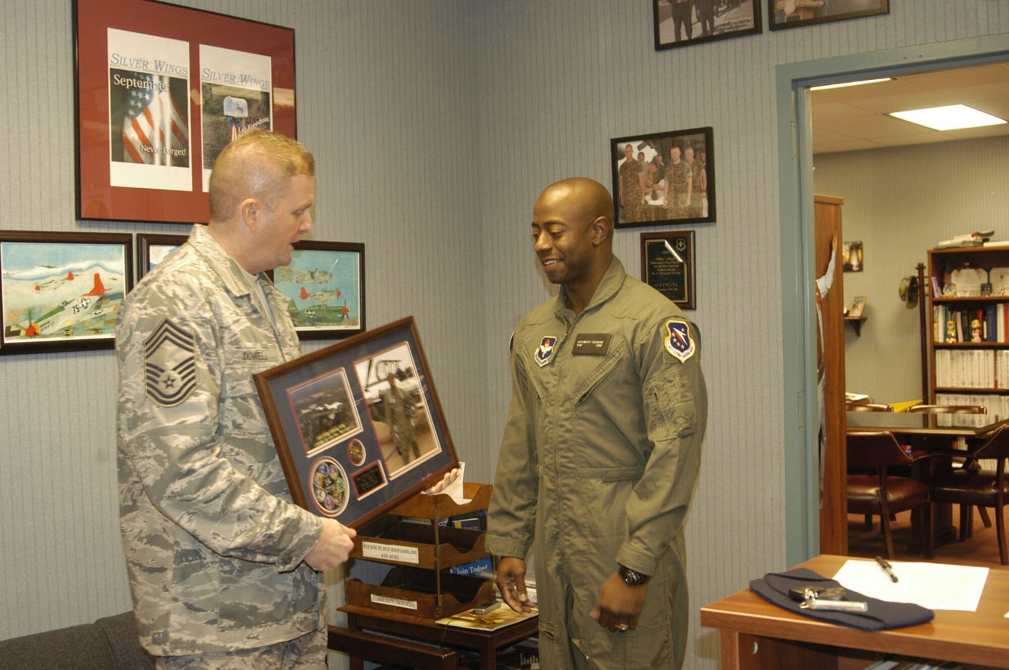 Chief Master Sgt. James Dowell, 14th Mission Support Group Superintendent, presents Tech. Sgt. Anthony Fleming, 332nd Recruiting Squadron, with a plaque to remember his T-6 Texan II orientation flight at Columbus AFB Tuesday. (U.S. Air Force photo by Airman 1st Class Danielle Hill)