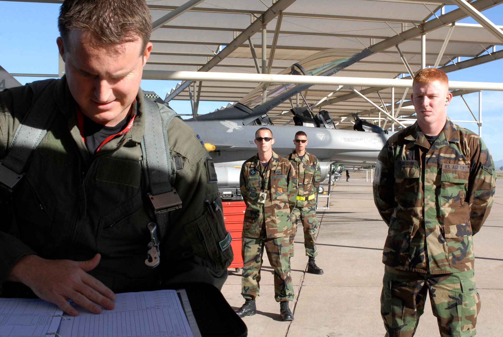 Captain David Wray, a 308th Fighter Squadron instructor pilot, checks over forms before his sortie as mission ready airmen look on, Feb. 26. Crew chief's attend MRA training at Luke Air Force Base, completing training that started at Sheppard Air Force Base, Tx. (photo by Staff Sgt. Christopher Hummel)