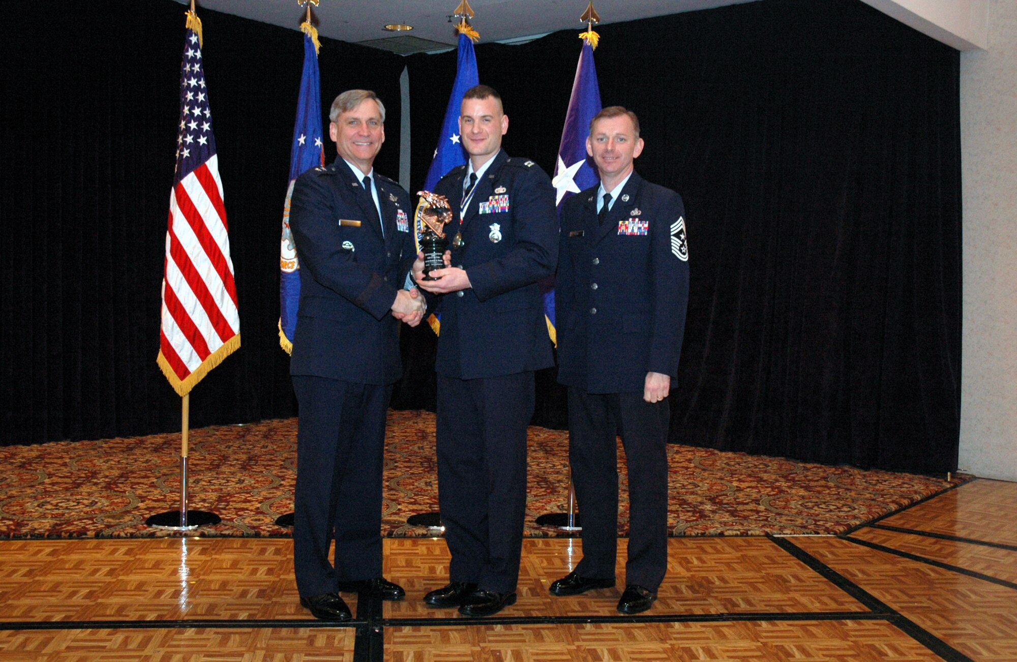 Maj. Gen. Kip Self, U.S. Air Force Expeditionary Center commander, presents Capt. Robert Prausa, 421st Combat Training Squadron, with the USAF EC Company Grade Officer of the Year Award for 2007 during the Center's annual awards luncheon Feb. 22, 2008, in the McGuire Air Force Base, N.J., Club.  Chief Master Sgt. Jeffry Helm, USAF EC command chief, was also on hand for the presentation.  (U.S. Air Force Photo/Tech. Sgt. Scott T. Sturkol)