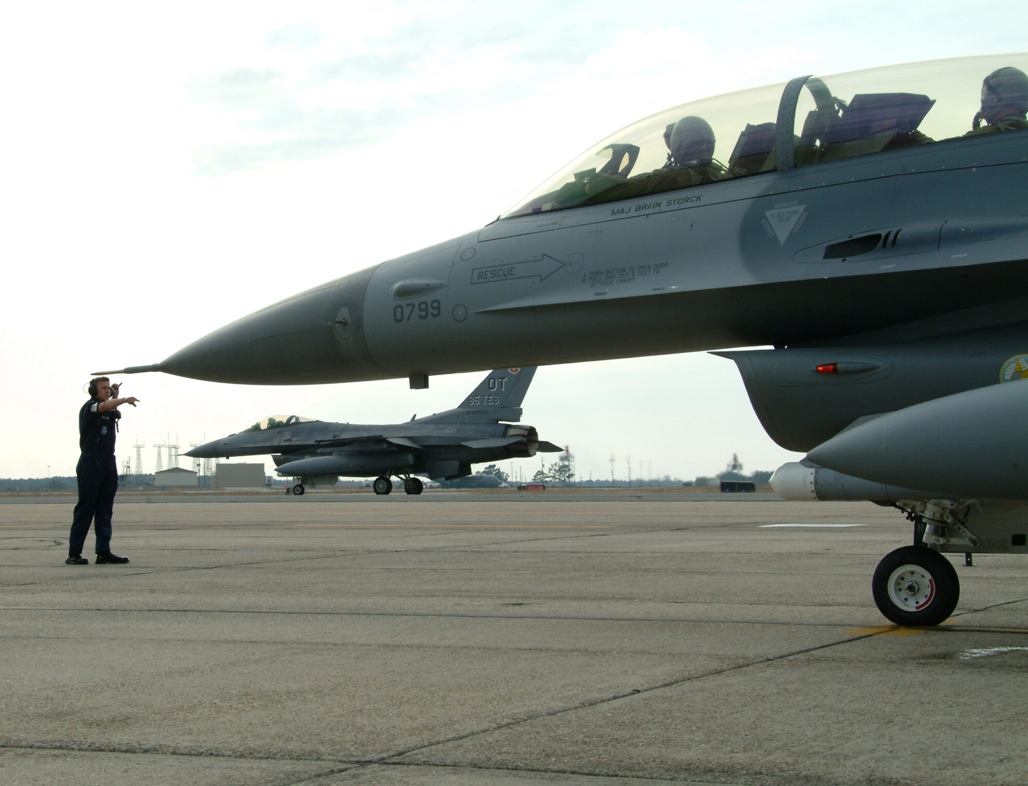 Airman Ryan Galler, 46th Aircraft Maintenance Squadron, clears Lt. Col. Eugene Booth, 86th Fighter Weapons Squadron, to taxi his F-16 Fighting Falcon out to the runway, while another F-16 from the 85th Test and Evaluation Squadron rolls by Feb. 26 at Eglin Air Force Base, Fla.  U.S. Air Force photo by Staff Sgt. Samuel King Jr.
