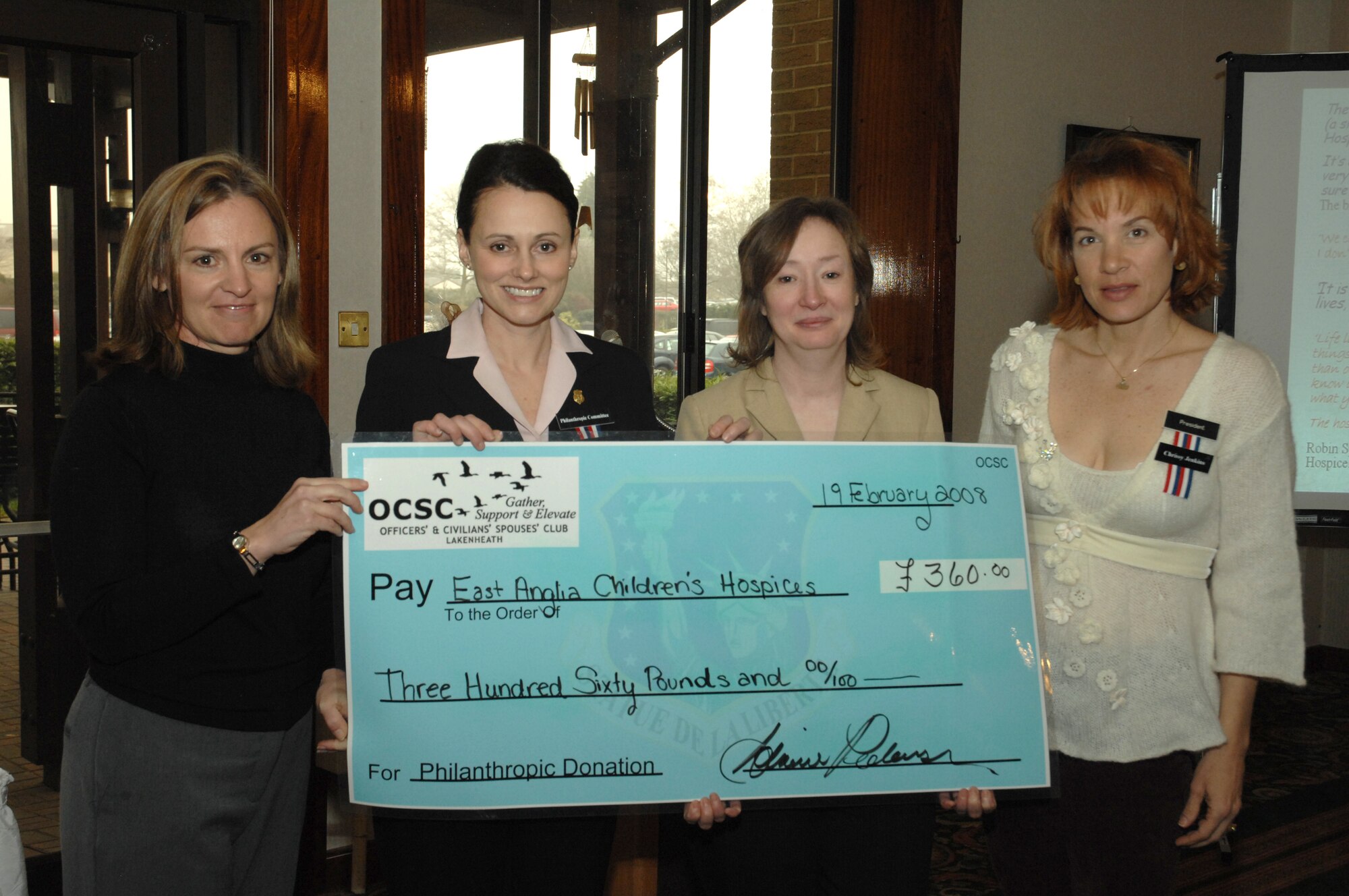 From left to right, Gisele Novak, Adriene Pederson, Sue Meader and Chrissy Jenkins, Officer and Civilian Spouses’ Club members, present a check to the East Anglia’s Children’s Hospice during a ceremony on Feb. 19 at the Eagles Landing at RAF Lakenheath, England. (U.S. Air Force photo by Airman 1st Class John Easterling)