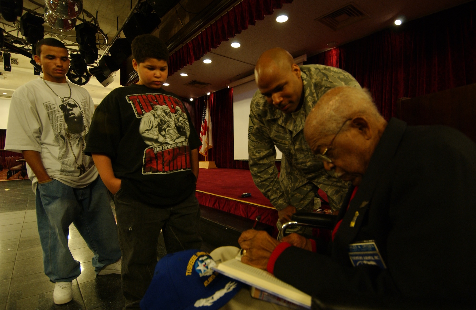 Retired Lt. Col. Charles W. Dryden, former Tuskegee Airman, signs his book, A-Train, for Master Sgt. Jonathan Curl, 18th Logistics Readiness Squadron traffic management superintendent, and his sons Derreck and Xavier, at the Rocker NCO Club Feb. 25. Sergeant Curl's grandfather was Colonel Dryden's crew chief during World War II. The colonel spoke to inform people the important role Tuskegee Airmen had during the war. 
(U.S. Air Force photo/Tech. Sgt. Rey Ramon)

