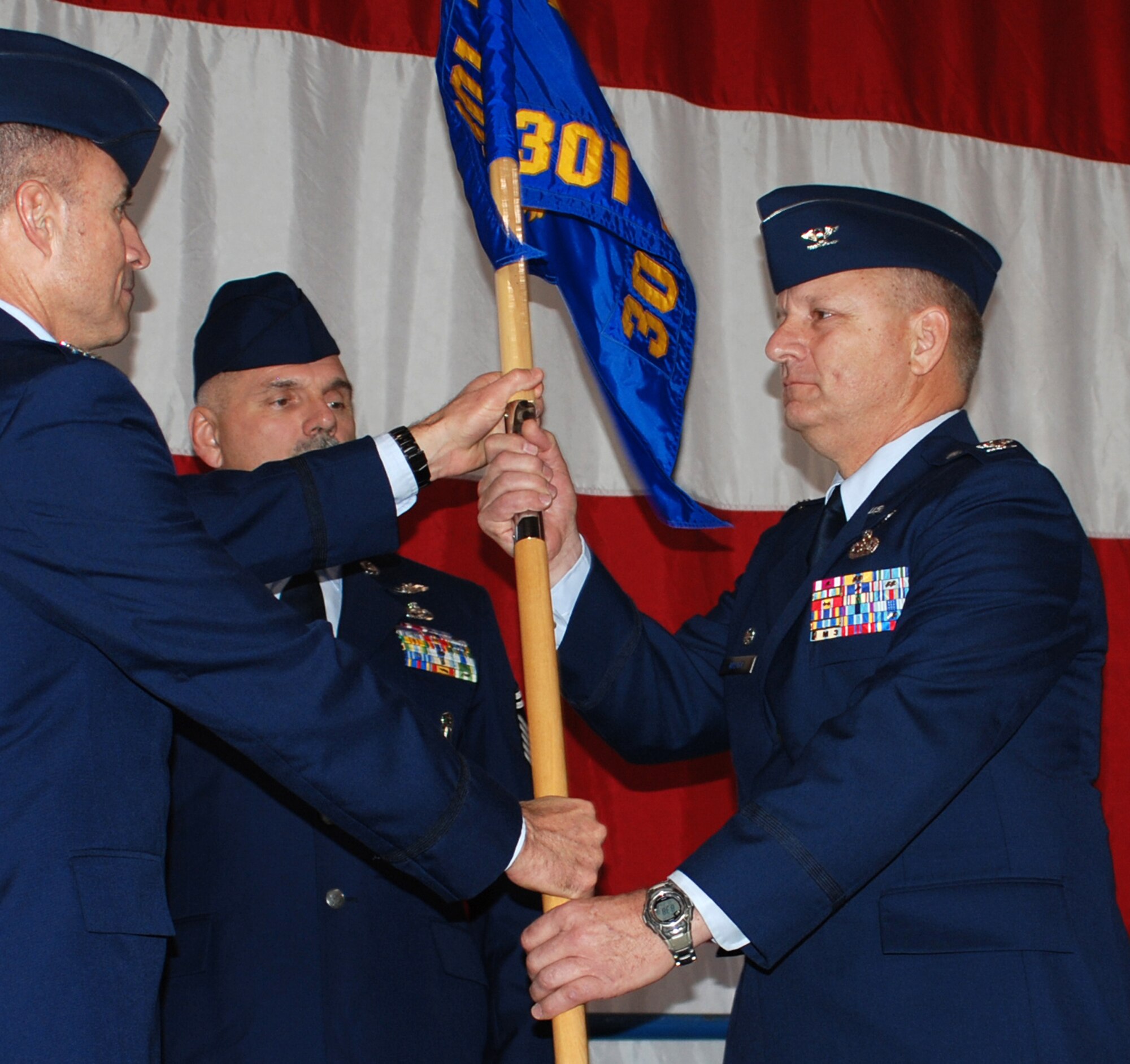 The new 301st Mission Support Group Commander, Col. Joylcon Walker, accepts the  MSG guidon from Col. Kevin E. Pottinger, 301st Fighter Wing commander, as Senior Master Sgt. Ben Combs looks on during a recent change of command ceremony at the Naval Air Station Joint Reserve Base Fort Worth, Texas. (U.S. Air Force Photo/Tech. Sgt. Stephen Bailey)
