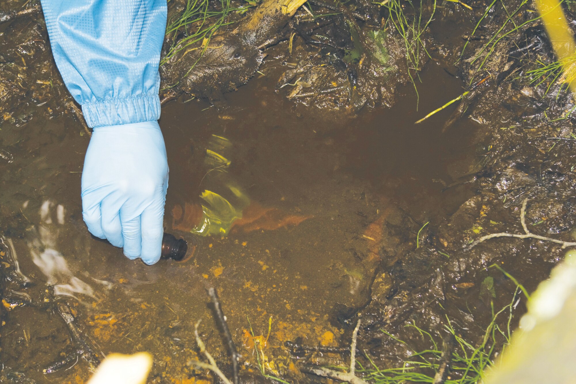 Kelly Carson, environmental scientist with Jacobs Engineering - Alaska Operations, conducts seep sampling at Knick Bluff Landfill. As part of the ongoing environmental monitoring program, samples of seeping groundwater are tested for contaminants. (Photo by Jacobs Engineering)
