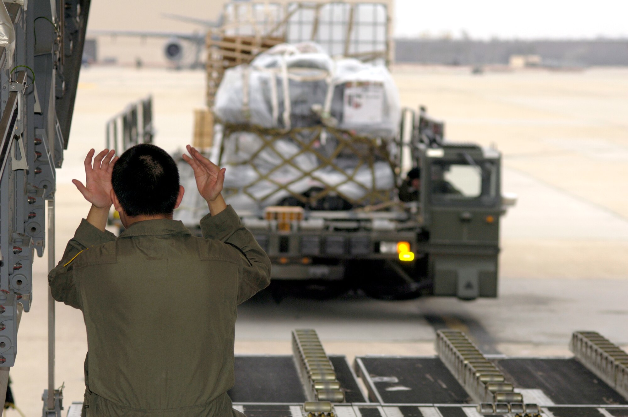 Senior Airman Miguel Leon marshals in supplies and equipment for Joint Task Force Operation Burnt Frost Feb. 20 at McGuire Air Force Base, N.J. The JTF was the recovery part of Operation Burnt Frost which covers the shoot down of the errant satellite loaded with hydrazine. The supplies were for 15 federal agencies tasked to handle the environmental effects of the satellite's reentry into the atmosphere. Airman Leon is a 6th Airlift Squadron loadmaster. (U.S. Air Force photo/Kenn Mann) 
