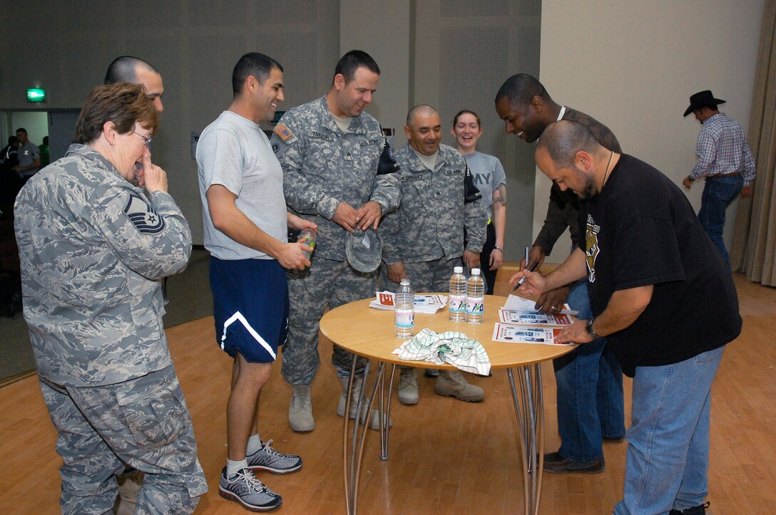 Comedians Bill Dykes (front right) and Danta Jackson share a laugh with Airmen from the 386th Expeditionary Air Wing as they autograph flyers following their Feb. 26 show at a Southwest Asia air base. The comedians are on a Multinational Corps Iraq, Army Morale Welfare Recreation, Lone Wolf Entertainment Comedy Tour 2008, which provides entertainment to deployed troops in support of operations Enduring Freedom and Iraqi Freedom. (U.S. Air Force photo/Staff Sgt. Patrick Dixon) 