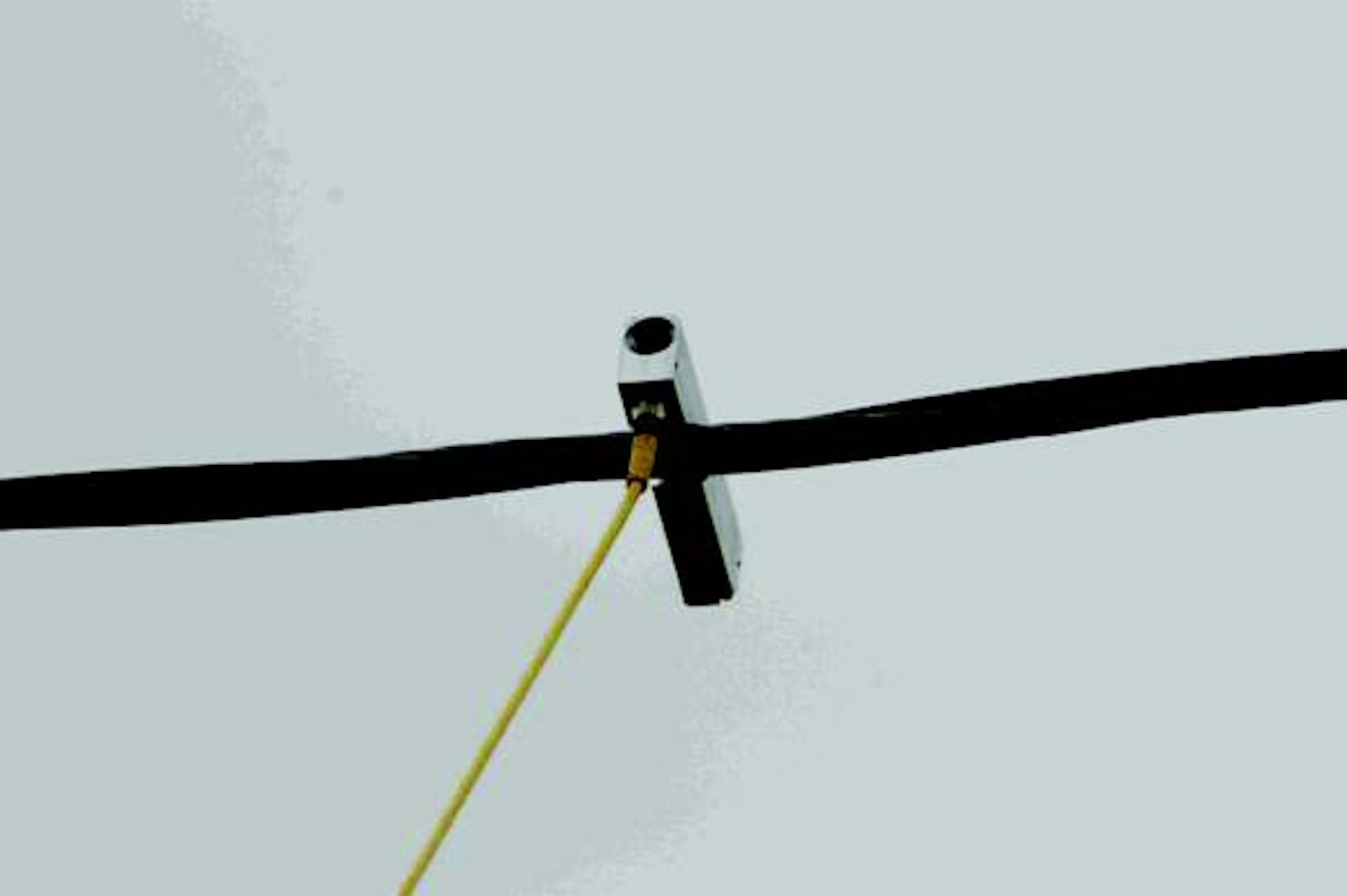 A remote auxiliary power system’s metal sensor head, nicknamed the “bat hook,” hangs over a power line.