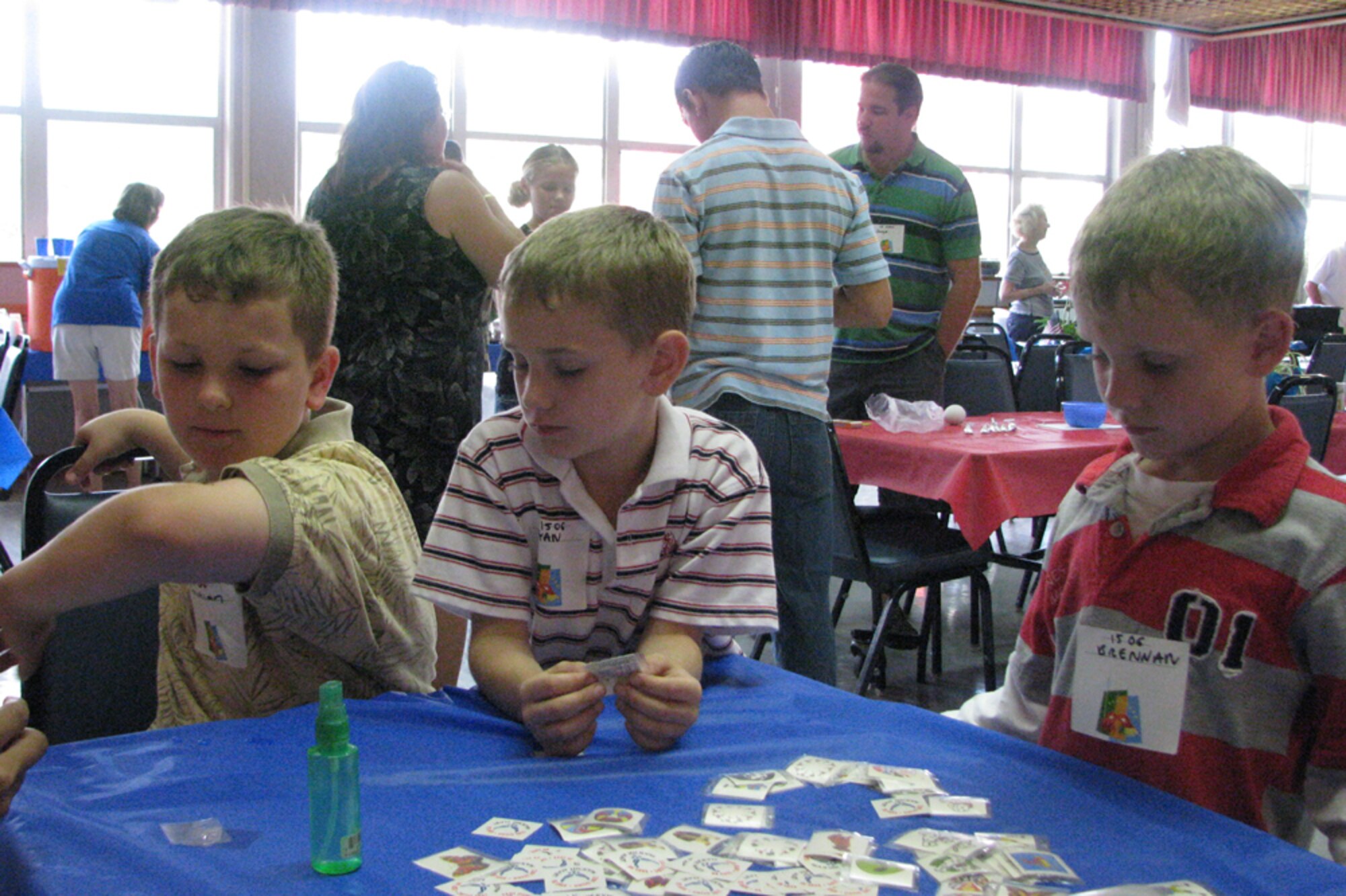 From left Christian, Ryan, and Brennan (sons of Capt Jason Ward, 15 OG/OGV) enjoy putting sticker tattoo on their arm during the monthly activity dinner at Nelles Chapel.  