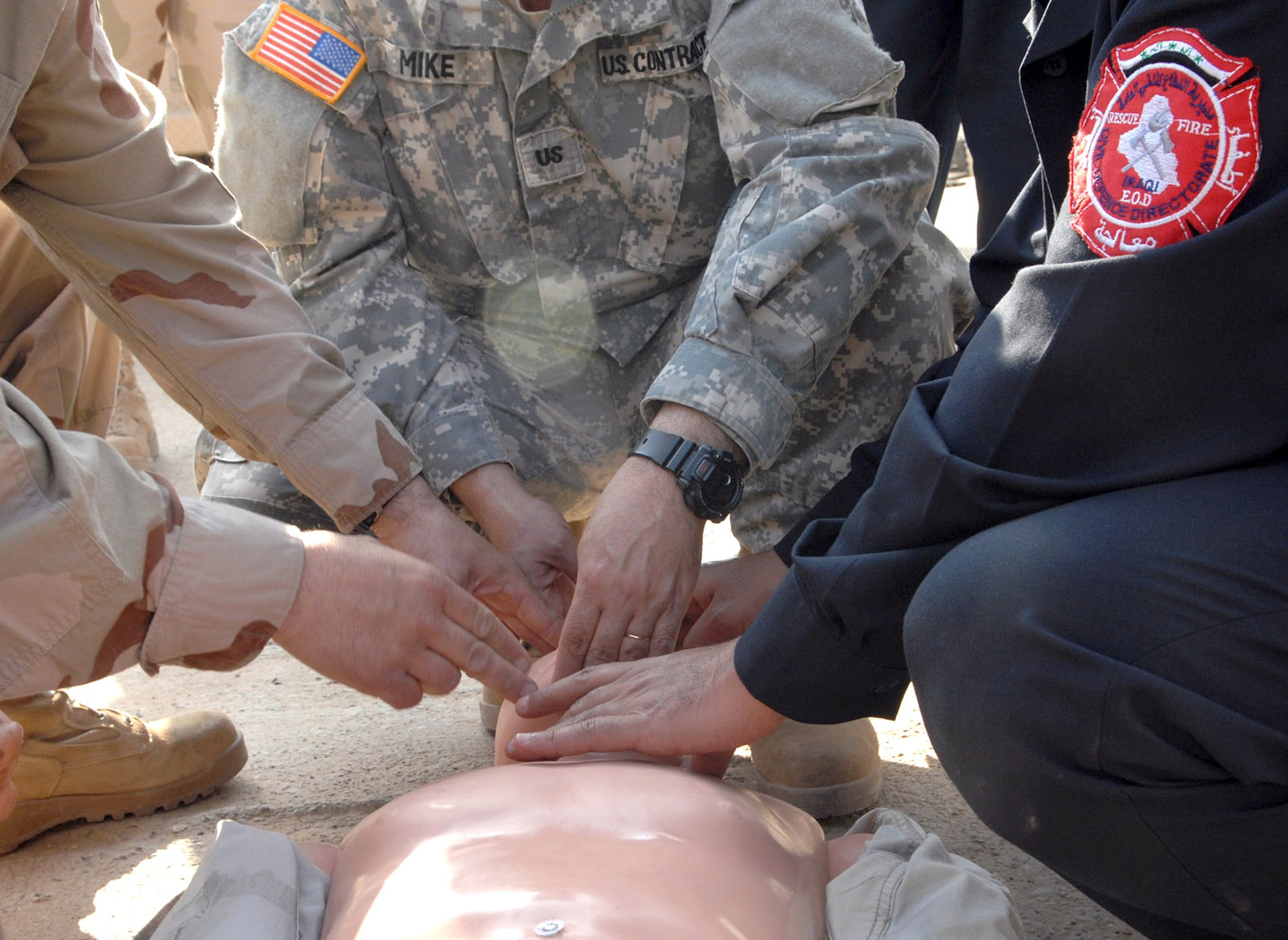 An Airman, Department of Defense contractor and Iraqi firefighter combine efforts to provide simulated CPR on a manikan Feb. 27 at Kirkuk Air Base, Iraq. The course is part of an ongoing program to help Kirkuk improve fire response efforts. (U.S. Air Force photo/Senior Airman SerMae Lampkin) 
