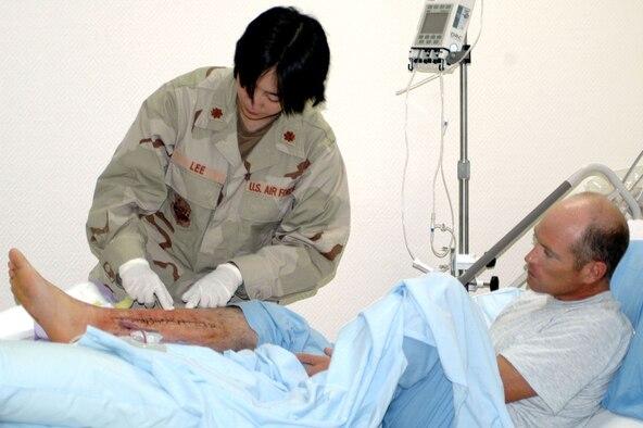 Left with nearly a foot-long scar along his shinbone, Staff Sgt. Stephen Jones knows he was lucky to survive a flesh-eating bacteria in his leg. Maj. (Dr.) Crystine Lee checks the status of Jones' leg as he recovers in the hospital after surgery. Jones says his pre-deployment training played a major role in his surviving the deadly bacterial infection. (U.S. Air Force photo by Senior Airman Cassandra Locke)