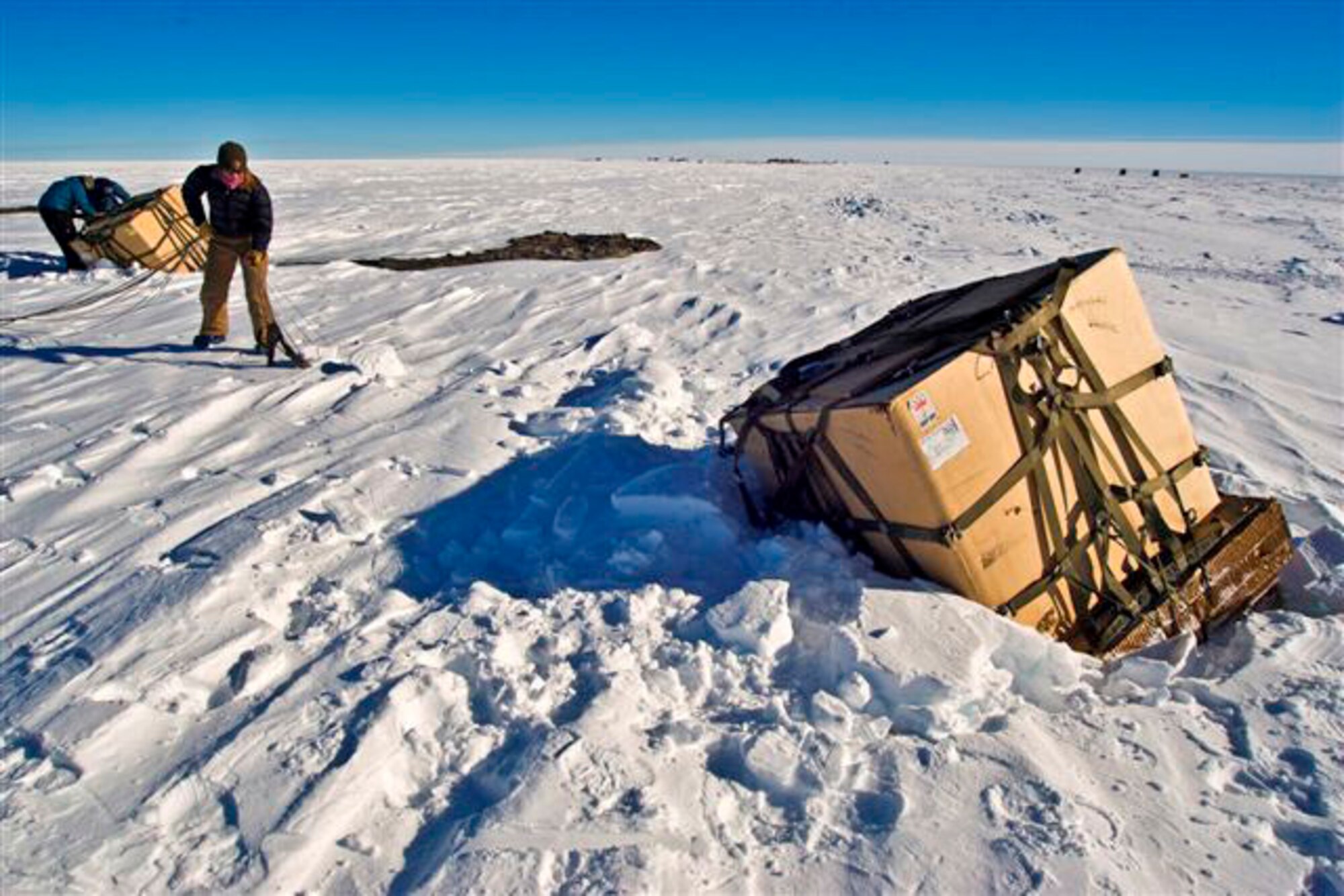Containerized delivery system bundles are recovered by a ground crew member at the South Pole. The bundles were airdropped by a McChord Air Force Base, Wash., C-17 Globemaster III supporting Operation Deep Freeze. The 13th Air Force-led Operation Deep Freeze is a unique joint and total force mission that has supported the National Science Foundation and U.S. Antarctic Program since 1955. By validating the C-17's capability to complete airdrop missions at the geographical South Pole, Joint Task Force-Support Forces Antarctica demonstrated its ability to provide mid-winter emergency re-supply and flexible support to the National Science Foundation and U.S. Antarctica Program. (Courtesy photo/B.K. Grant) 