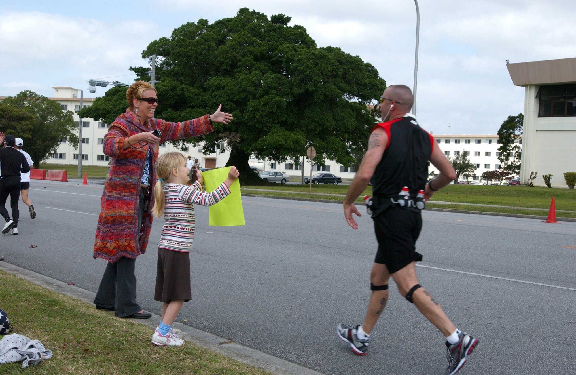 Maj. Todd Harding, Garrison Mobile Equipment Fleet manager, Camp Foster, is greeted with a hug from his wife, Erin, and daughter, Karen, as he reaches the 30 kilometer mark for the 16th Okinawa Marathon Sunday. (U.S. Air Force photo/Senior Airman Jeremy McGuffin)