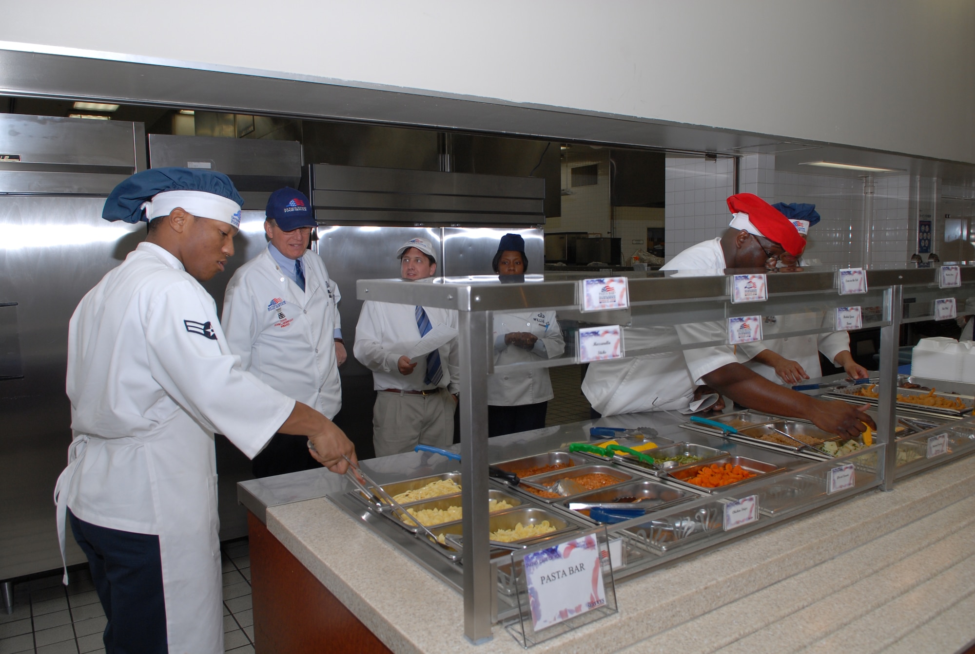 YOKOTA AIR BASE, Japan-- Airman 1st Class Rayshawn  Fountain places a set of tongs into a tray of noodles and Staff Sgt Robert Wynter checks the teperature of potatoes on the food line while being looked on by Mr. George Miller, Head Quarters Air Force Services Agent  Hennesy Award judge, at the Samuria Cafe here Feb. 28. The Hennesy team goes to different dinning facilities through out the Pacific Air Force and inspects and judges of variety of items for the Hennesy Award.