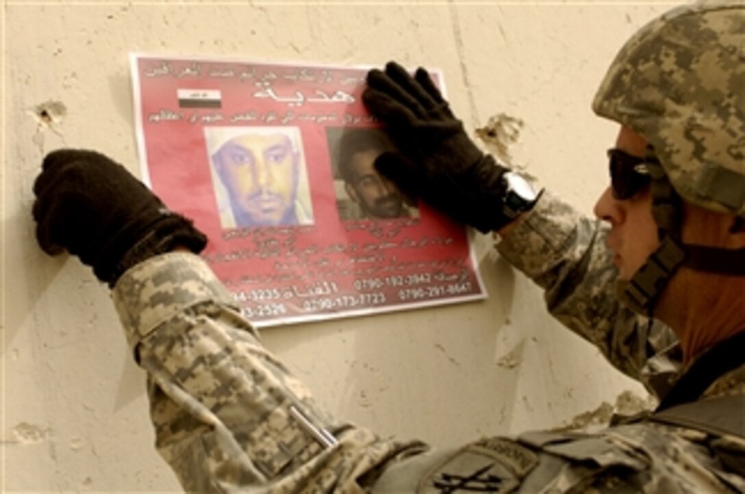 U.S. Army Sgt. 1st Class Sam MacKenzie from Alpha Company, 13th Psychological Operations Battalion puts up wanted posters near the Ministry of Interior building in Rusafa, Iraq, on Feb. 27, 2008.  