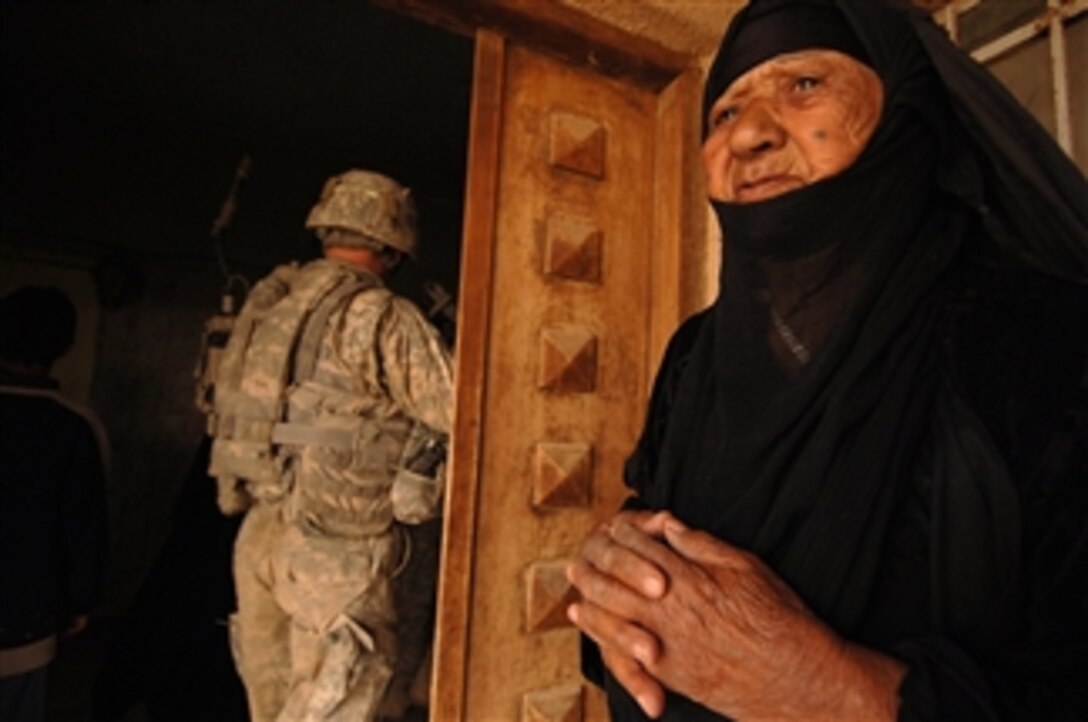 An elderly Iraqi woman stands aside and watches as U.S. Army soldiers from Bravo Company, 1st Battalion, 15th Infantry Regiment, 3rd Heavy Brigade Combat Team, 3rd Infantry Division pass by to search her house during a clearing operation in Kesra, Iraq, on Feb. 24, 2008. 
