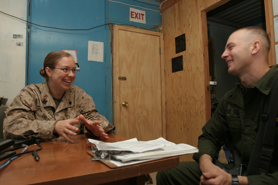 AT - TAQADDUM, Iraq - Navy Lt. Megan K. Smith, deputy staff judge advocate, Marine wing headquarters squadron 3, speaks to Cpl. Darius P. Sanojca, air framer, from Fair Lawn, N.J., about his taxes here, Feb. 29. Being able to provide this opportunity to file taxes while service members are on deployment, gives Smith, from Petersburg, Ill., a sense of accomplishment.
