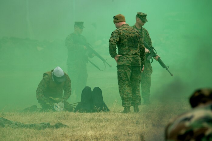 Working near flash-bang grenades and thick smoke bombs, hospital corpsmen assess and assist simulated wounded victims on the ground during a Tactical Combat Casualty Care exercise conducted at the paintball range here Feb. 29. They were being evaluated by Petty Officer 2nd Class Christopher P. Utz, Marine Aircraft Group 12 aero-medical safety corpsman, who coordinated the course.