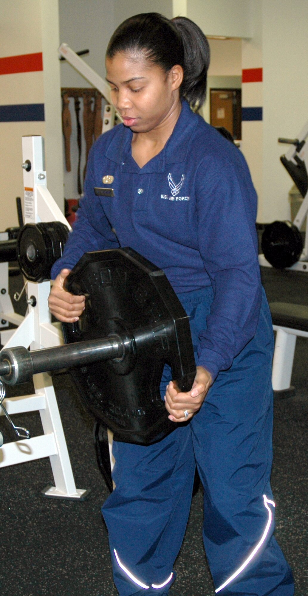 Senior Airman Chanice Leonard, a fitness specialist with the 341st Services Squadron, removes weight plates from the bar in the weight room at the Sports and Fitness Center. Airman Leonard will be working on New Year's Day. (U.S. Air Force photo/Valerie Mullett)