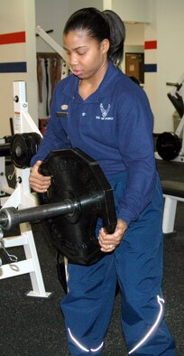 Senior Airman Chanice Leonard, a fitness specialist with the 341st Services Squadron, removes weight plates from the bar in the weight room at the Sports and Fitness Center. Airman Leonard will be working on New Year's Day. (U.S. Air Force photo/Valerie Mullett)