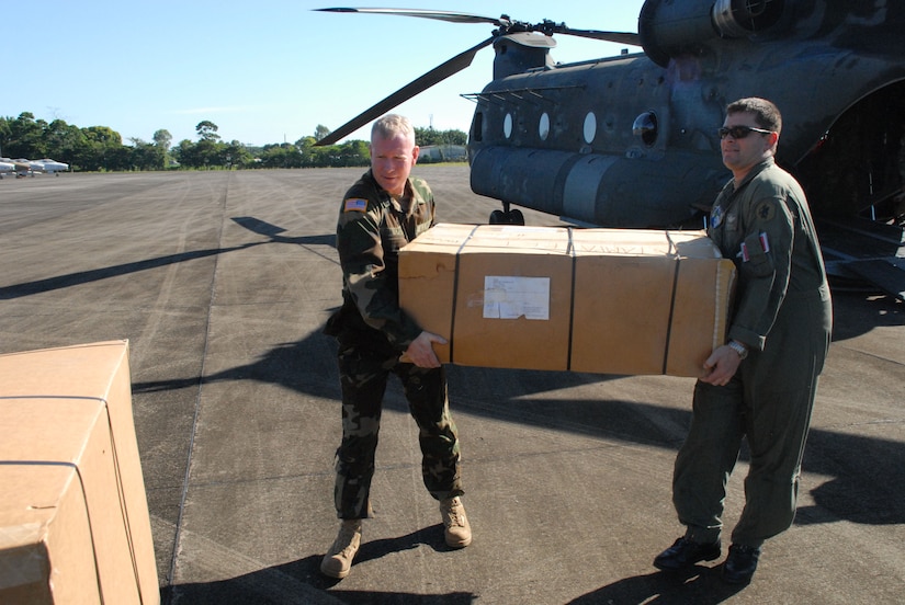 LA CEIBA, Honduras - (Left) Army Lt. Col. Todd Conyers, 1st Battalion, 228th Aviation Regiment commander, and Army Staff Sgt. Daniel Glick, also with the 1/228, offload donated wheelchairs from a CH-47 Chinook helicopter here Dec. 28.  The hand-crank wheelchairs were donated to isolated villages along the Miskito Coast of Honduras.  The Alabama non-profit organization Missions Unlimited contacted the U.S. Agency for International Development to coordinate the donation. (U.S. Air Force photo by Tech. Sgt. Sonny Cohrs) 