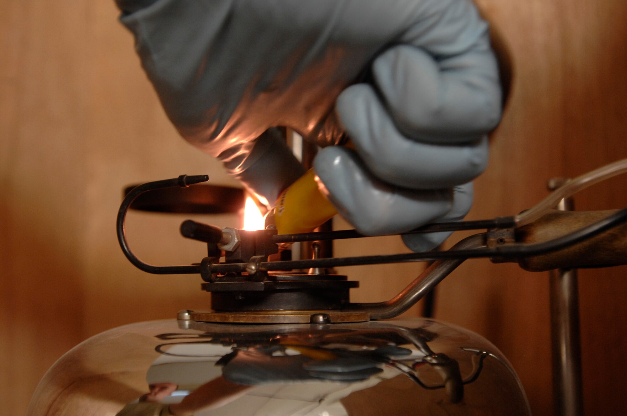 ALI AIR BASE, Iraq -- Senior Airman Jay Pickle lights the heating device to test the flash point of a fuel sample by heating the sample up and checking every two degrees until the sample creates a flash at around 110 degrees Dec. 28. A sample of fuel must be tested for every fuel shipment received to ensure the quality meets the strict standards to be used in Air Force aircraft. He is assigned to the 407th Expeditionary Logistics Readiness Squadron and is deployed from Yokota Air Base, Japan. (U.S. Air Force photo/Airman 1st Class Jonathan Snyder)