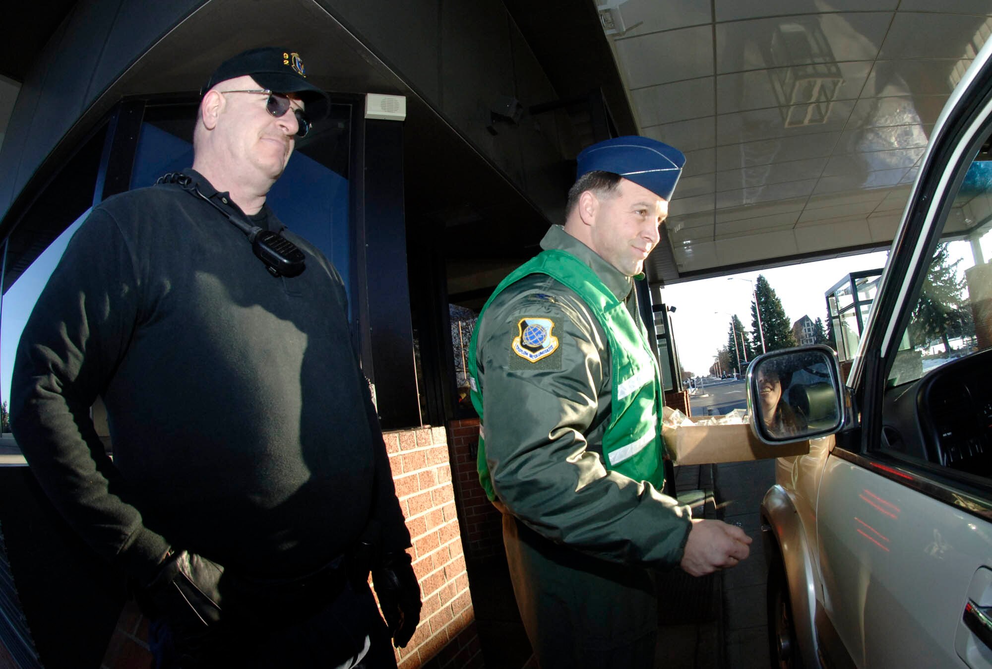 FAIRCHILD AIR FORCE BASE, Wash. – Col. Thomas Sharpy, 92nd Air Refueling Wing commander, passes out candy canes and wishes individuals a happy holiday as they pass through the main gate on Dec. 21 as Bill Cartwright, Department of Defense security guard, looks on.(U.S. Air Force photo /Staff Sgt. JT May III)
