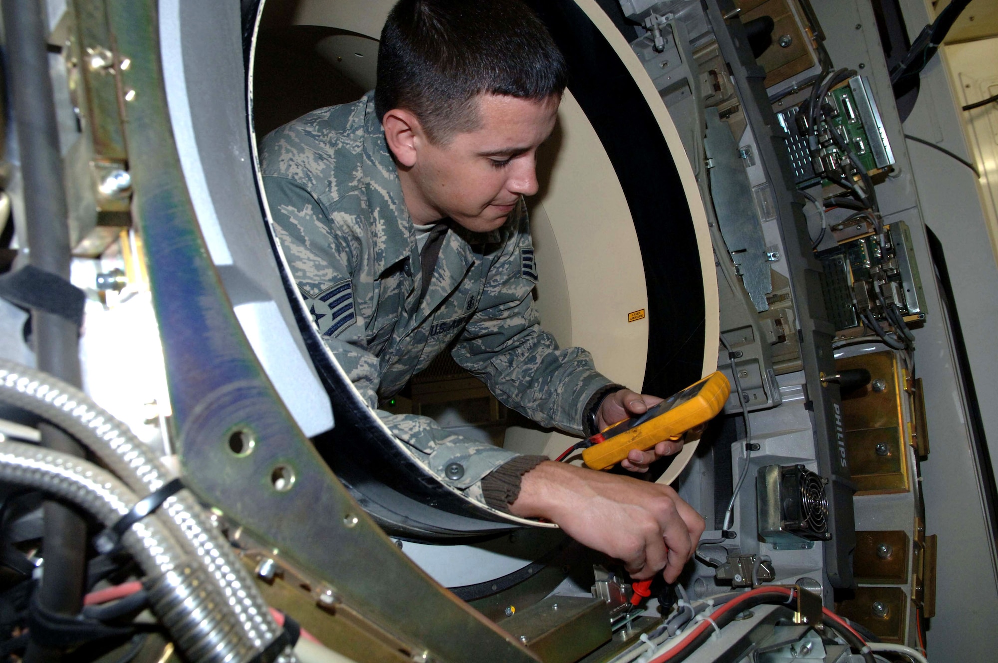 Staff Sgt. Orlando Ortega looks at a multimeter to check the voltage readings inside a computerized tomography machine Dec. 31 at the Air Force Theater Hospital at Balad Air Base, Iraq. The CT machine provides doctors a three dimensional internal image of a patient taken from a series of angles. Biomedical equipment repair technicians here perform repairs, scheduled maintenance, inspections and calibrations on all biomedical equipment. Sergeant Ortega is a 332nd Expeditionary Medical Support Squadron biomedical equipment technician deployed from Barksdale Air Force Base, La. (U.S. Air Force photo/Senior Airman Terri Barriere)
