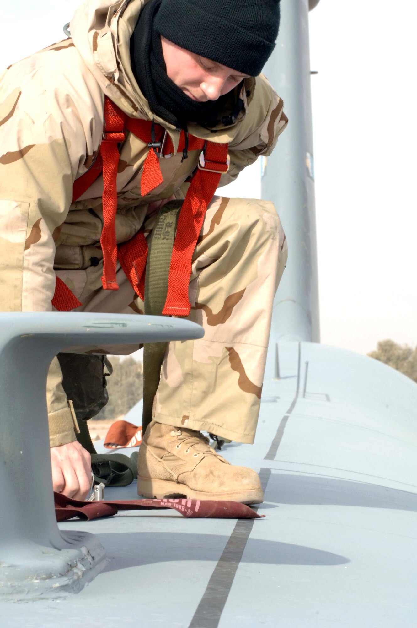 Airman 1st Class Chris Olmstead attaches his safety harness to the safety rail of a C-5 Galaxy before performing maintenance on the aircraft Jan. 1 at Balad Air Base, Iraq. The gigantic C-5, with its tremendous payload capability, provides airlift in support of the war on terrorism. The C-5 can carry fully equipped combat-ready military units to any point in the world on short notice and then provide field support required to help sustain the fighting force. Airman Olmstead is a 721st Air Mobility Operations Group crew chief deployed from Travis Air Force Base, Calif. (U. S. Air Force photo/Senior Airman Terri Barriere)