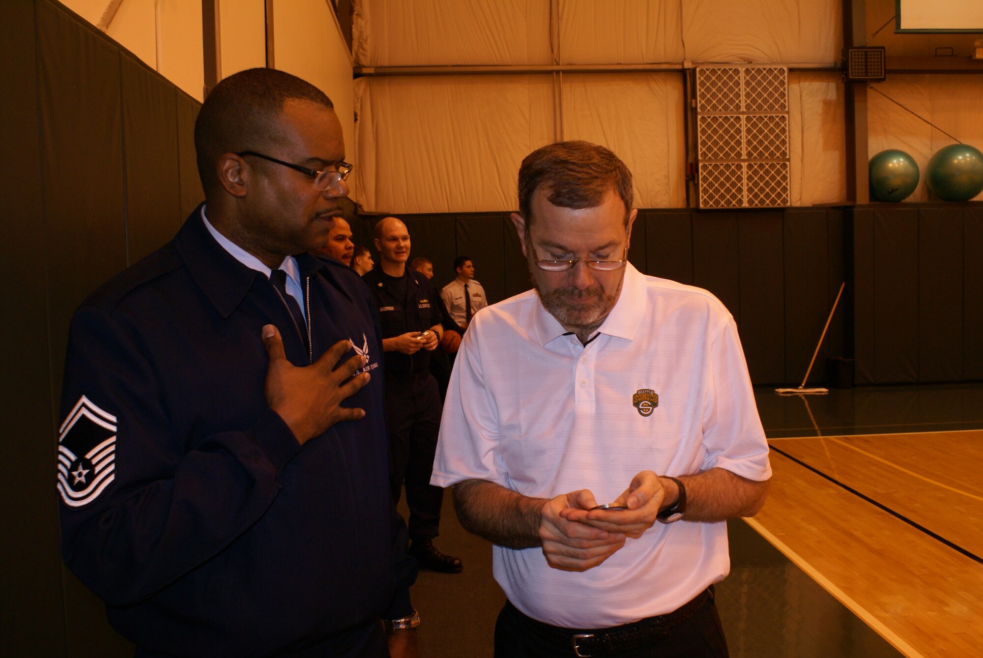 Senior Master Sgt. Stephen Harris, 446th Services Flight, presents Sonics coach P.J.
Carlesimo with a military challenge coin.