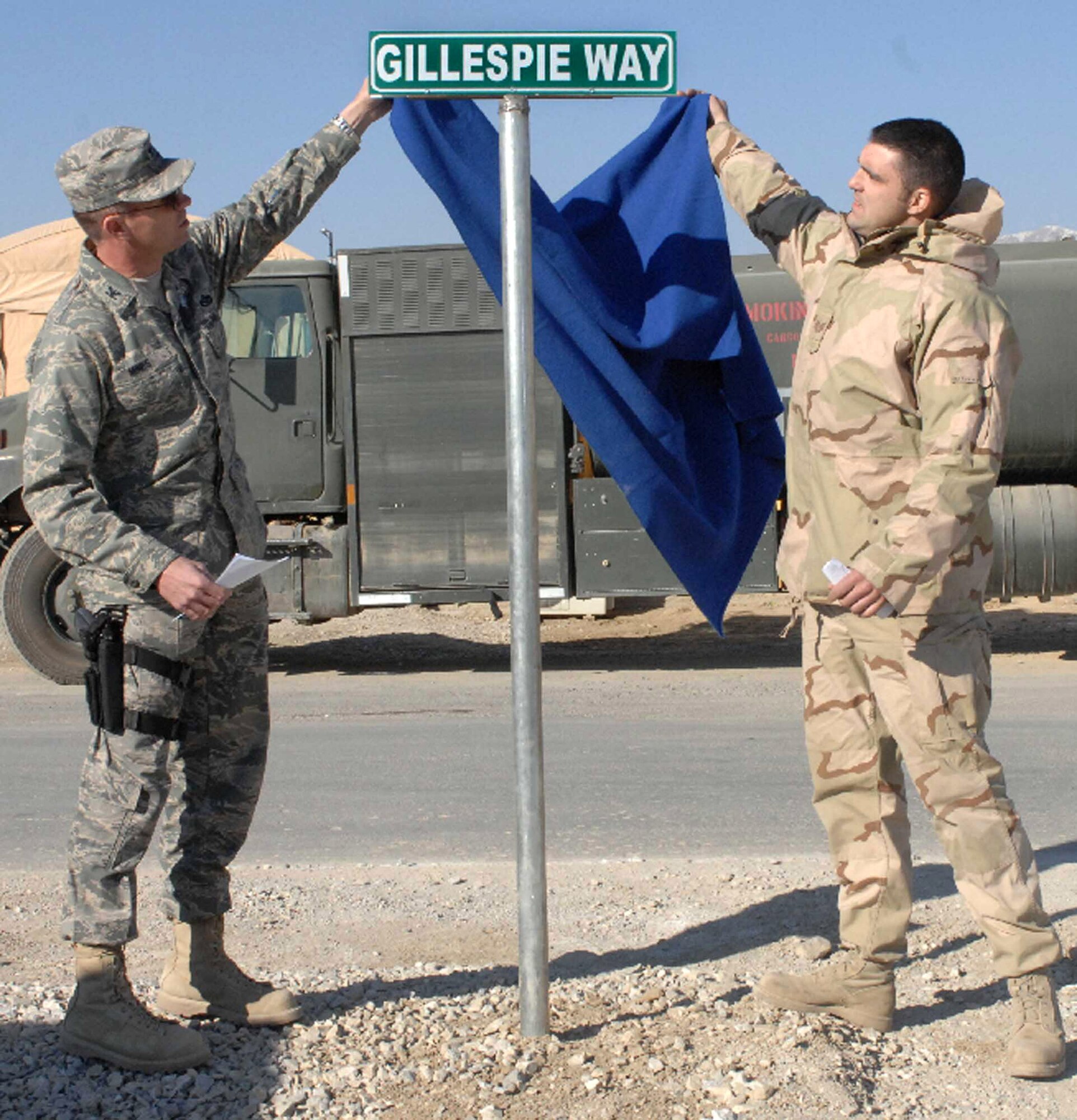 Col. Barry Mines and Tech. Sgt. Blaine Arsenault unveil a sign dedicating a road to the memory of fallen Airmen Master Sgt. Randy Gillespie Dec. 1at Bagram Air Base, Afghanistan. Sergeant Gillespie was a career fuels specialist who died July 9 from wounds sustained during small arms fire near Herat, Afghanistan. Colonel Mines is the 455th Expeditionary Mission Support Group commander and Sergeant Arsenault is a 455th Expeditionary Logistics Readiness Squadron fuels specialist. (U.S. Air Force Photo/Capt. Michael Meridith)