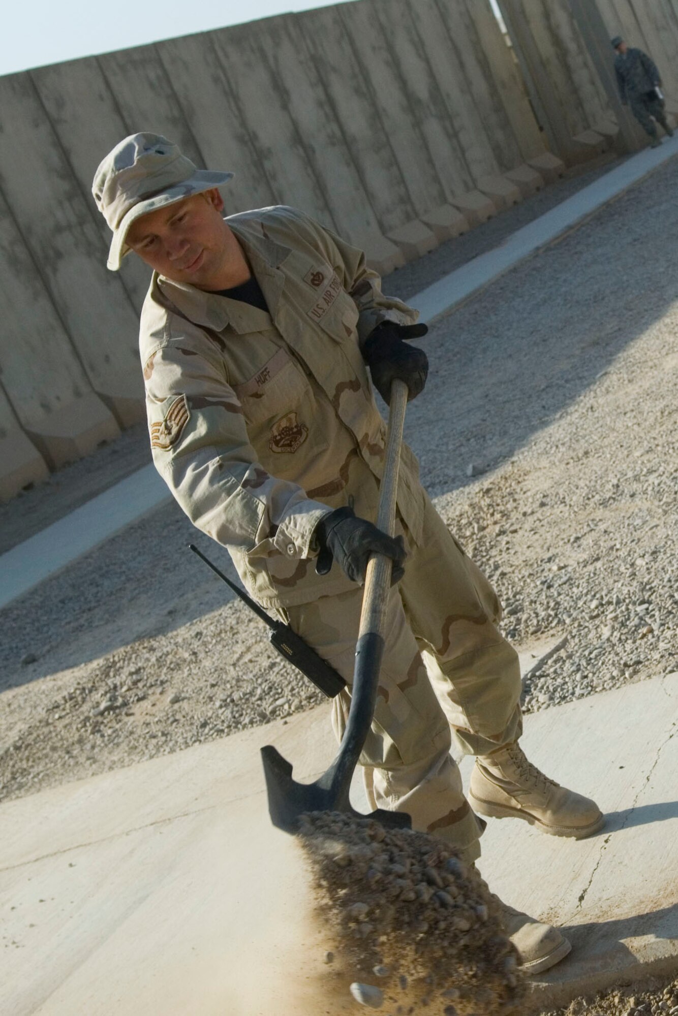 BALAD AIR BASE, Iraq -- Staff Sgt. William Huff, a 332nd Expeditionary Civil Engineer Squadron heavy equipment operator, removes rocks and dirt from the sidewalk after completing work here, Dec. 3. The team cut into the soil approximately three inches deep to reach a harder surface before laying gravel in preparation for mud season. Sergeant Huff is deployed from Patrick Air Force Base, Fla. (U.S. Air Force photo /Staff Sgt. Travis Edwards)