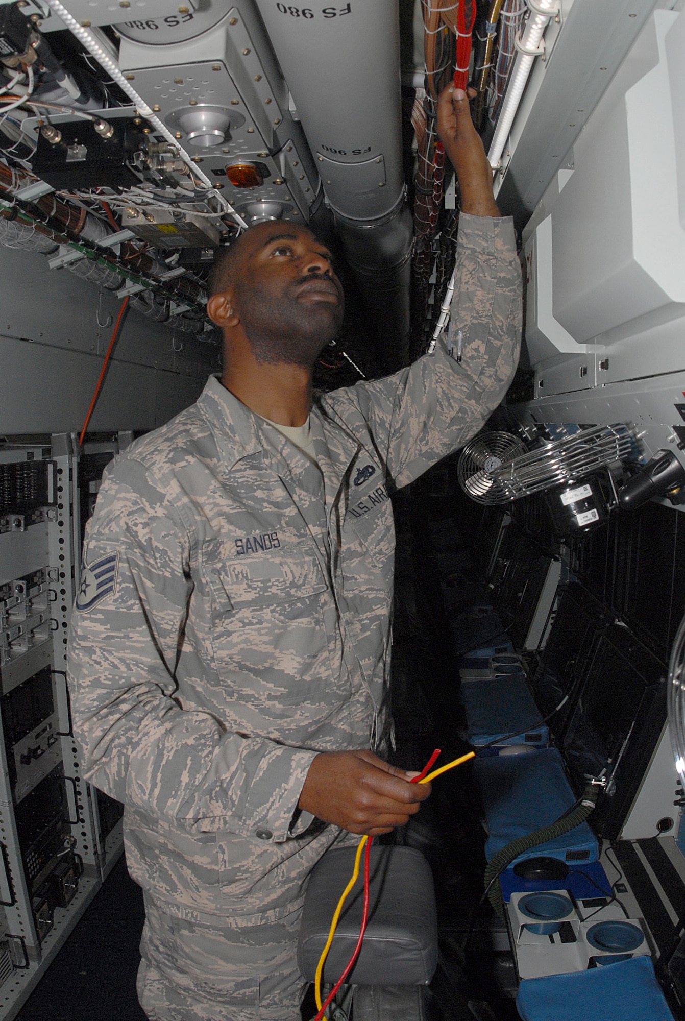 SOUTHWEST ASIA - Staff Sgt. David Sands, 763rd Expeditionary Reconnaissance Squadron ground radio technician, lays out a cable run on board an RC-135 Rivet Joint aircraft at a Southwest Asia air base Jan. 3. Once installed, the cables will provide the aircrew with an internet-like connection between selected stations on board the aircraft and the ground. The 763 ERS is a tenant unit of the 379th Air Expeditionary Wing. Sergeant Sands is deployed from Lackland Air Force Base, Texas, and is from Fayetteville, N.C. (U. S. Air Force photo/Staff Sgt. Douglas Olsen)