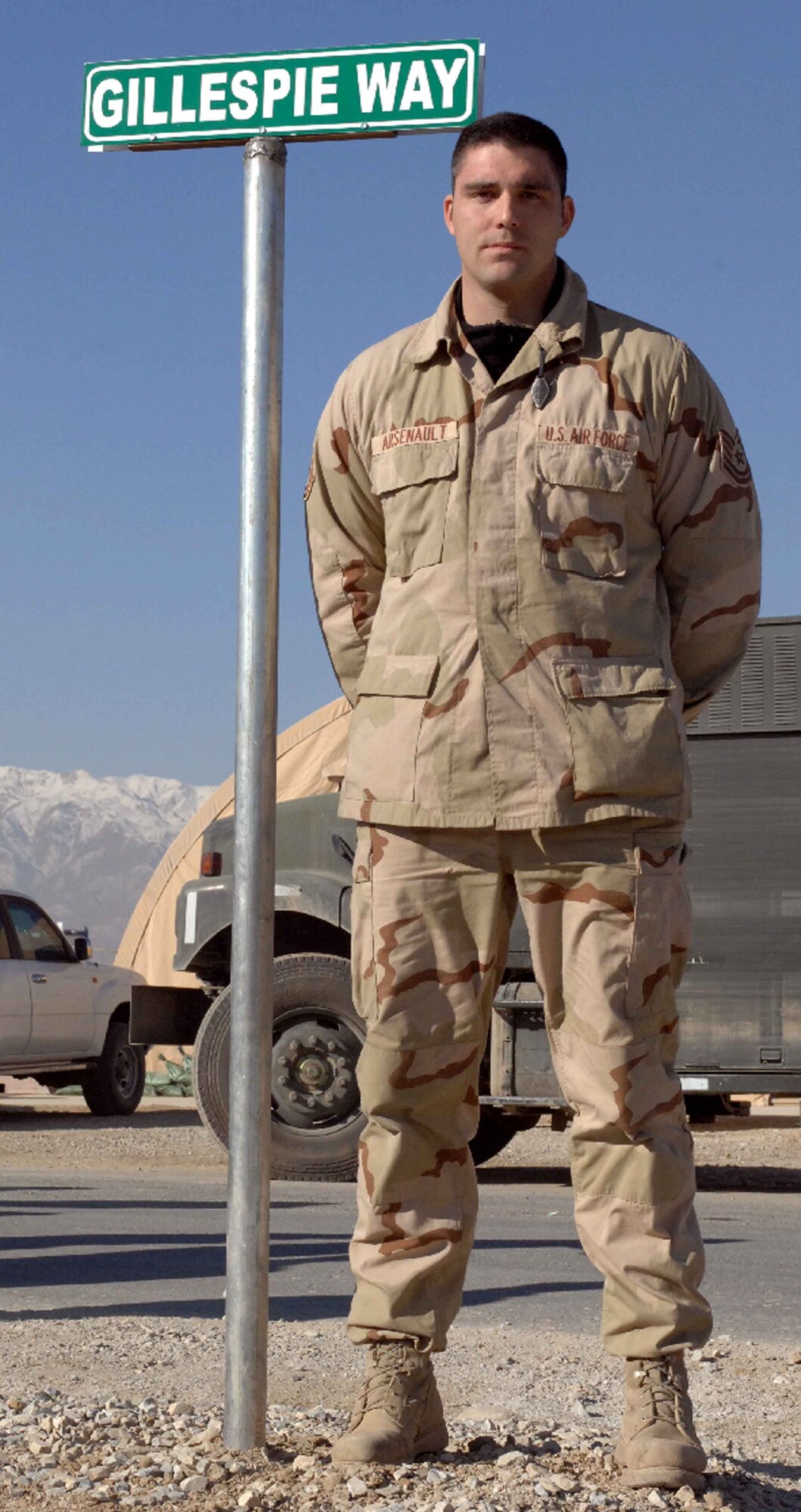 BAGRAM AIR BASE, Afghanistan - Tech. Sgt. Blaine Arsenault, 455th Expeditionary Logistics Readiness Squadron, stands by a sign dedicating a road near the fuel farm here to the memory of fallen Airmen Master Sgt. Randy Gillespie, Jan. 1, 2008.  Sergeant Gillespie was Sergeant Arsenault's first supervisor and a career fuels specialist who died July 9, 2007 from wounds sustained during small arms fire near Herat, Afghanistan. (U.S. Air Force Photo by Capt. Mike Meridith)