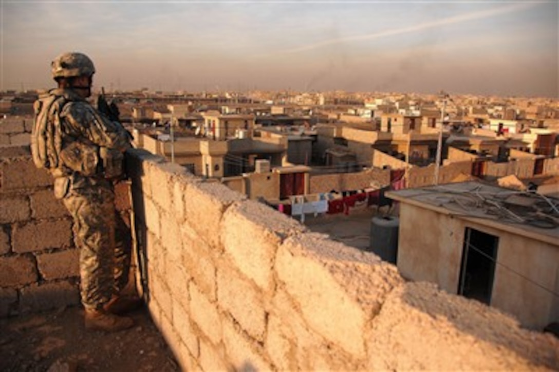 A U.S. Army soldier watches the neighborhood from a rooftop as he provides security for his fellow soldiers in Mosul, Iraq, on Dec. 25, 2007.  Soldiers from the 3rd Armor Calvary Regiment are investigating a house destroyed by a bomb earlier that day. 