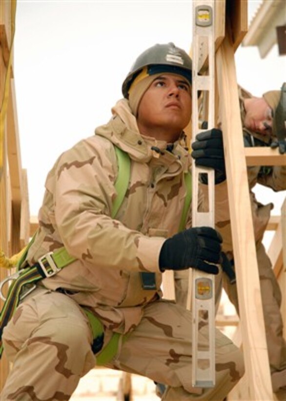 U.S. Navy Seabee Petty Officer 3rd Class Adam Turbeville checks the plumb of a truss while working on the construction of a fellowship hall at Camp Ramadi, Iraq, on Dec. 20, 2007.  The hall will be used to host conferences, celebrations and worship services, and will also serve as a place for service members to relax.  Turbeville is a Navy Builder assigned to Naval Mobile Construction Battalion 1.  