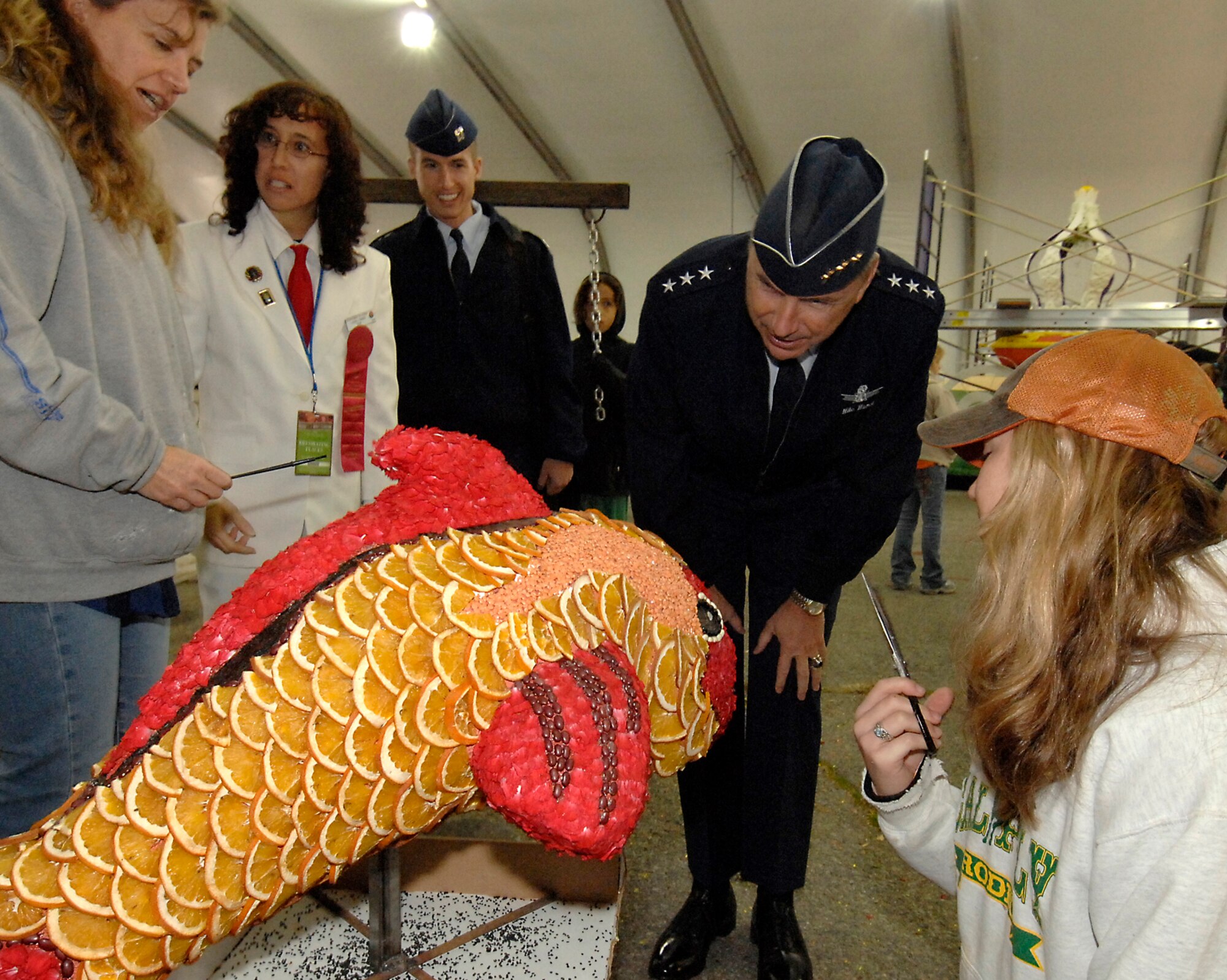 Workers use orange slices as fish scales on a Tournament of Rose float. SMC Commander Lt. Gen. Michael Hamel and his family toured the float decoration area, Dec. 30. (Photo by Joseph Juarez)