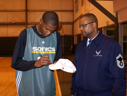 Kevin Durant of the NBA's Seattle Sonics basketball team signs a hat for Senior Master Sgt. Stephen Harris at KeyArena in Seattle Dec. 19.  Sergeant Harrison, a Reservist with the 446th Services Flight at McChord Air Force Base, Wash., was one of 20 military members from McChord and Fort Lewis invited to spend the day with the Sonics as a thank you to all military personnel. (U.S. Air Force photo/Tyler Hemstreet)           