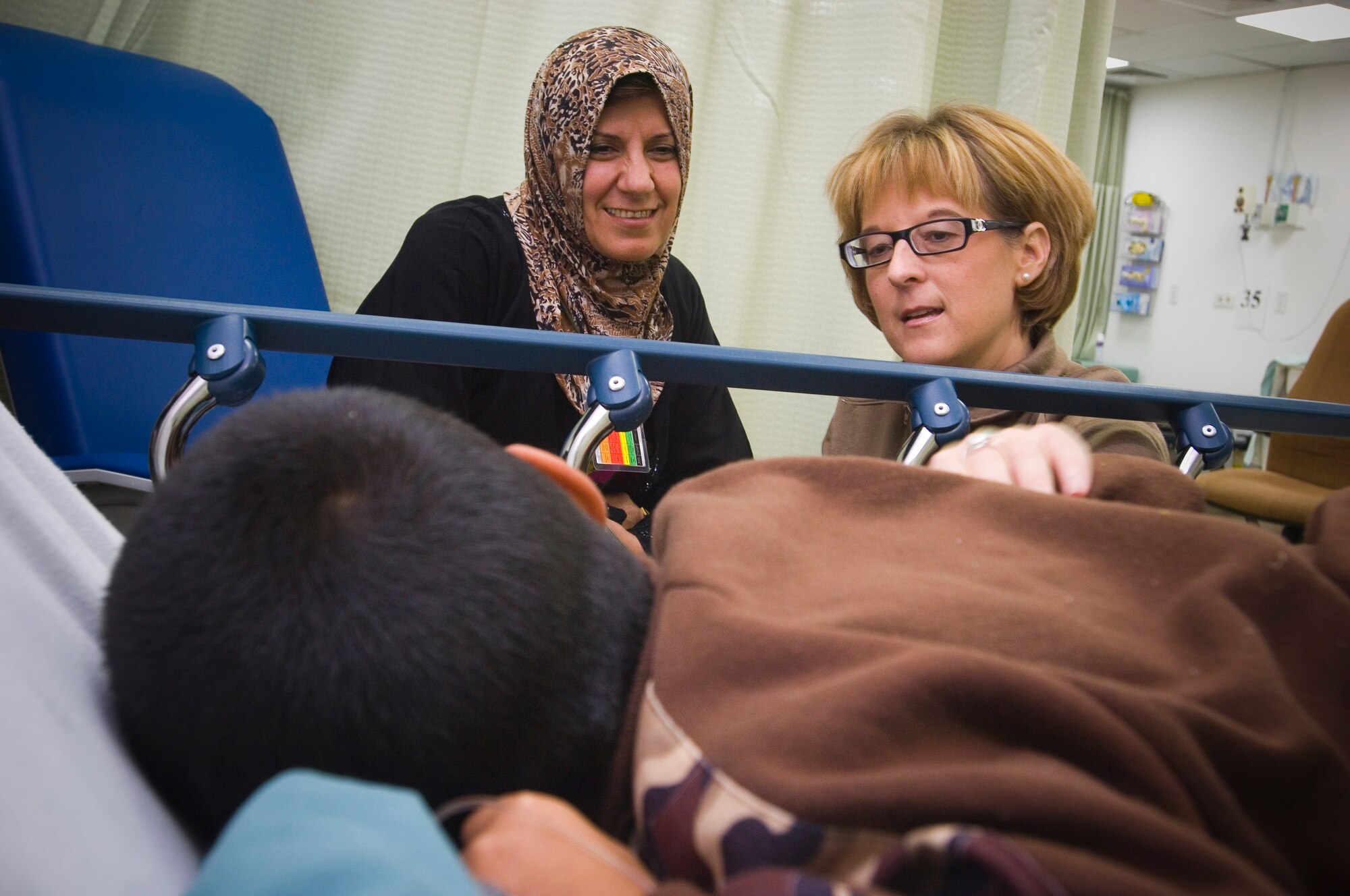 BALAD AIR BASE, Iraq -- Maj. Rebecca Cypher, an intermediate care ward nurse, checks on a wounded Iraqi boy with the child's mother at the Air Force Theater Hospital here. Many of the major's patients at the ICW are sick or injured Iraqi children and adults who can't receive or afford quality medical care. Major Cypher is deployed from Wilford Hall Medical Center, San Antonio, Texas. (U.S. Air Force photo/Tech. Sgt. D. Clare)