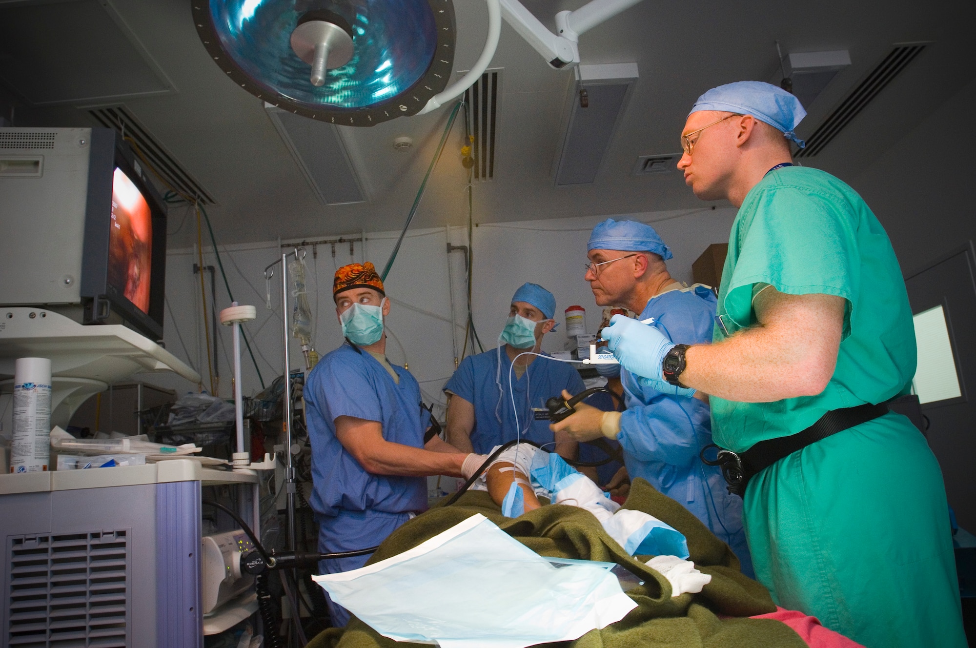 BALAD AIR BASE, Iraq -- Capt. Charlie Johnson, left, a certified registered nurse anesthetist, holds a patient in place during an endoscopy procedure at the Air Force Theater Hospital here. Captain Johnson earned his CRNA certification while serving as an Air Force nurse. He is deployed from Travis Air Force Base, Calif. (U.S. Air Force photo/Tech. Sgt. D. Clare)