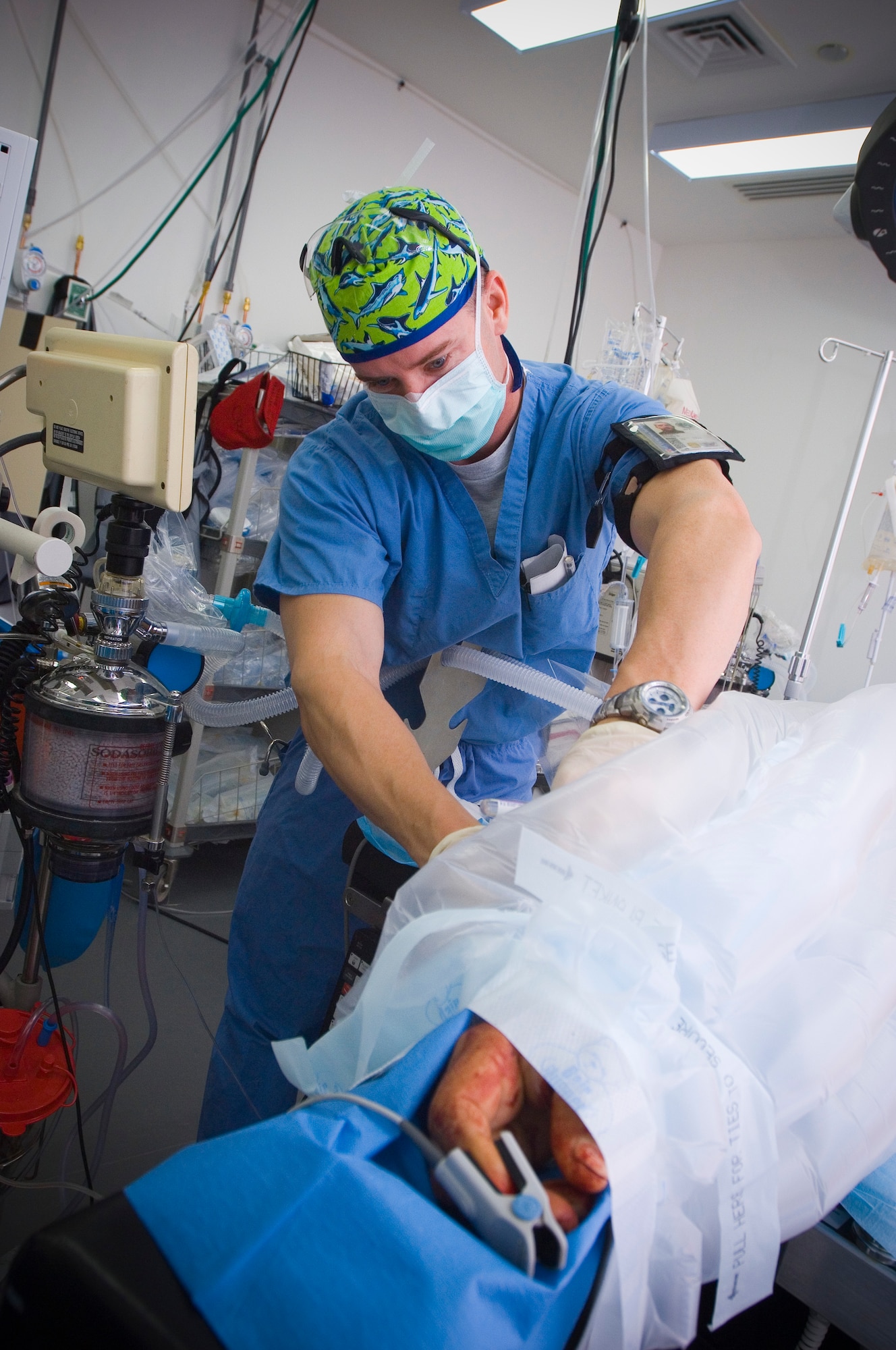 BALAD AIR BASE, Iraq -- Capt. Charlie Johnson, a certified registered nurse anesthetist, ties down a temperature regulator on a patient before a surgical procedure at the Air Force Theater Hospital here. The device allows him to maintain the patient's body temperature during operation. Captain Johnson is deployed from Travis Air Force Base, Calif. (U.S. Air Force photo/Tech. Sgt. D. Clare)