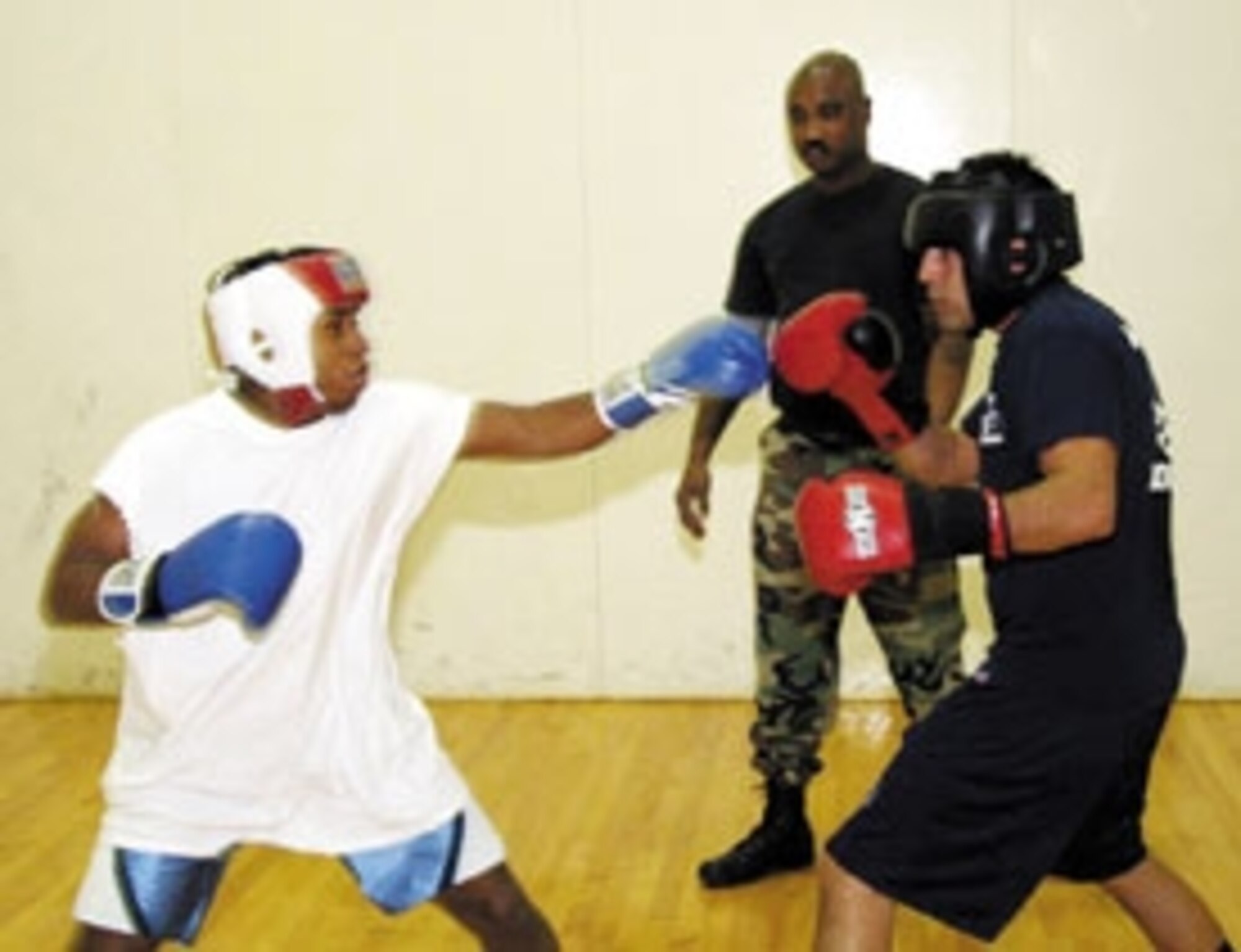 Under the watchful eye of their coach, Tech. Sgt. Gordon Hodges, Airman 1st Class James Carr, left, and Staff Sgt. Richard Mora, right, spar against each other last week in preparation for their fight on Saturday. (Air Force photo by Darren D. Heusel)