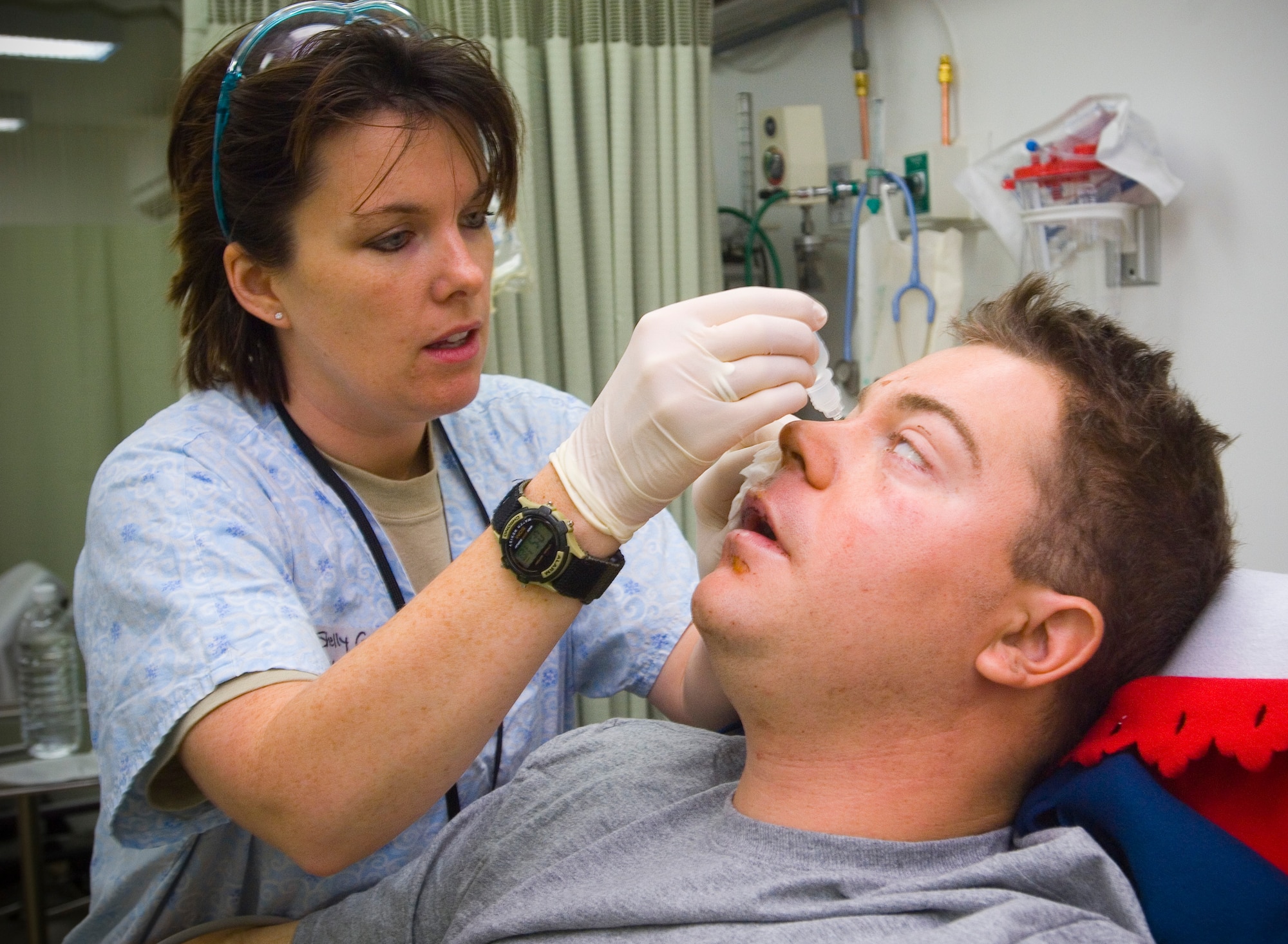 BALAD AIR BASE, Iraq -- Capt. Shelly Garceau, an emergency room nurse, gives Spc. Christopher Burrell eye drops at the Air Force Theater Hospital here. Specialist Burrell, a member of the 108th Military Police Company, suffered burns and lost his leg as a result of an explosive formed penetrator in an attack near Sadr City. Capt. Garceau is deployed from Wilford Hall Medical Center, San Antonio, Texas. (U.S. Air Force photo/Tech. Sgt. D. Clare)