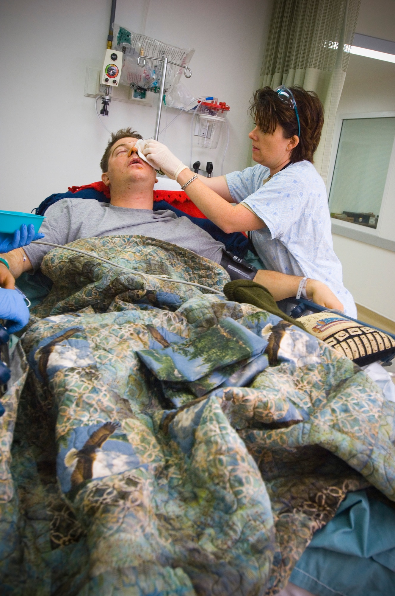 BALAD AIR BASE, Iraq -- Capt. Shelly Garceau, an emergency room nurse, attends to Spc. Christopher Burrell's face at the Air Force Theater Hospital here. Specialist Burrell, a member of the 108th Military Police Company, suffered burns and lost his leg as a result of an explosive formed penetrator in an attack near Sadr City. Capt. Garceau is deployed from Wilford Hall Medical Center, San Antonio, Texas. (U.S. Air Force photo/Tech. Sgt. D. Clare)