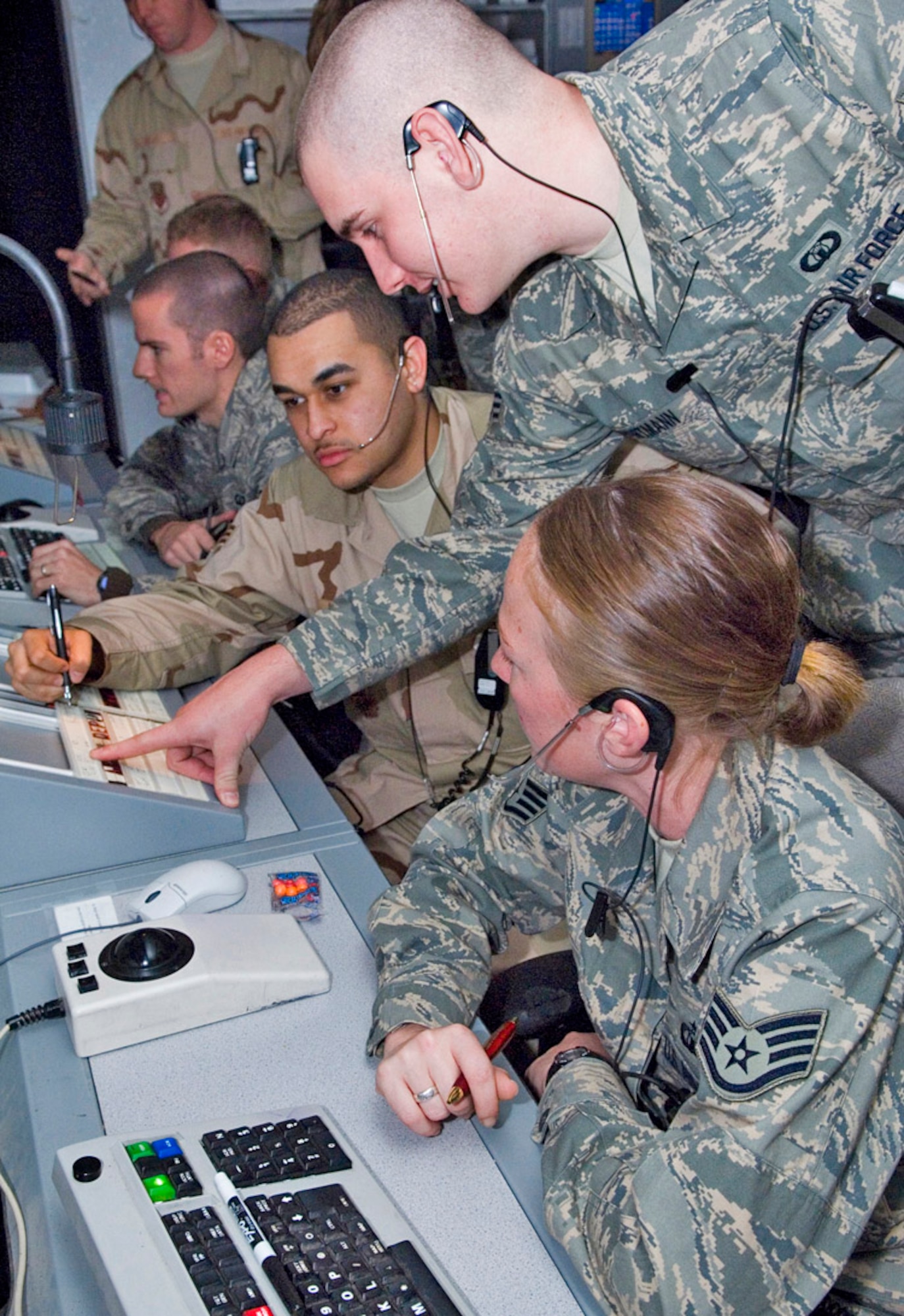 Senior Airman Aaron Portman, working in the flight data position at Balad Air Base, Iraq, points out the altitude at which an inbound aircraft will be traveling to Senior Airman David Daniel, (seated), and Staff Sgt. Elizabeth Deem.  All are 332nd Expeditionary Operations Support Squadron air traffic controllers. Airman Daniel and Sergeant Deem are working as approach control assistants. Airman Daniel is deployed from Royal Air Force Lakenheath, England; Airman Portman is a from Dover Air Force Base, Del.; and Sergeant Deem is deployed from Vance AFB, Okla. (U.S. Air Force photo/Senior Airman Travis Edwards) 