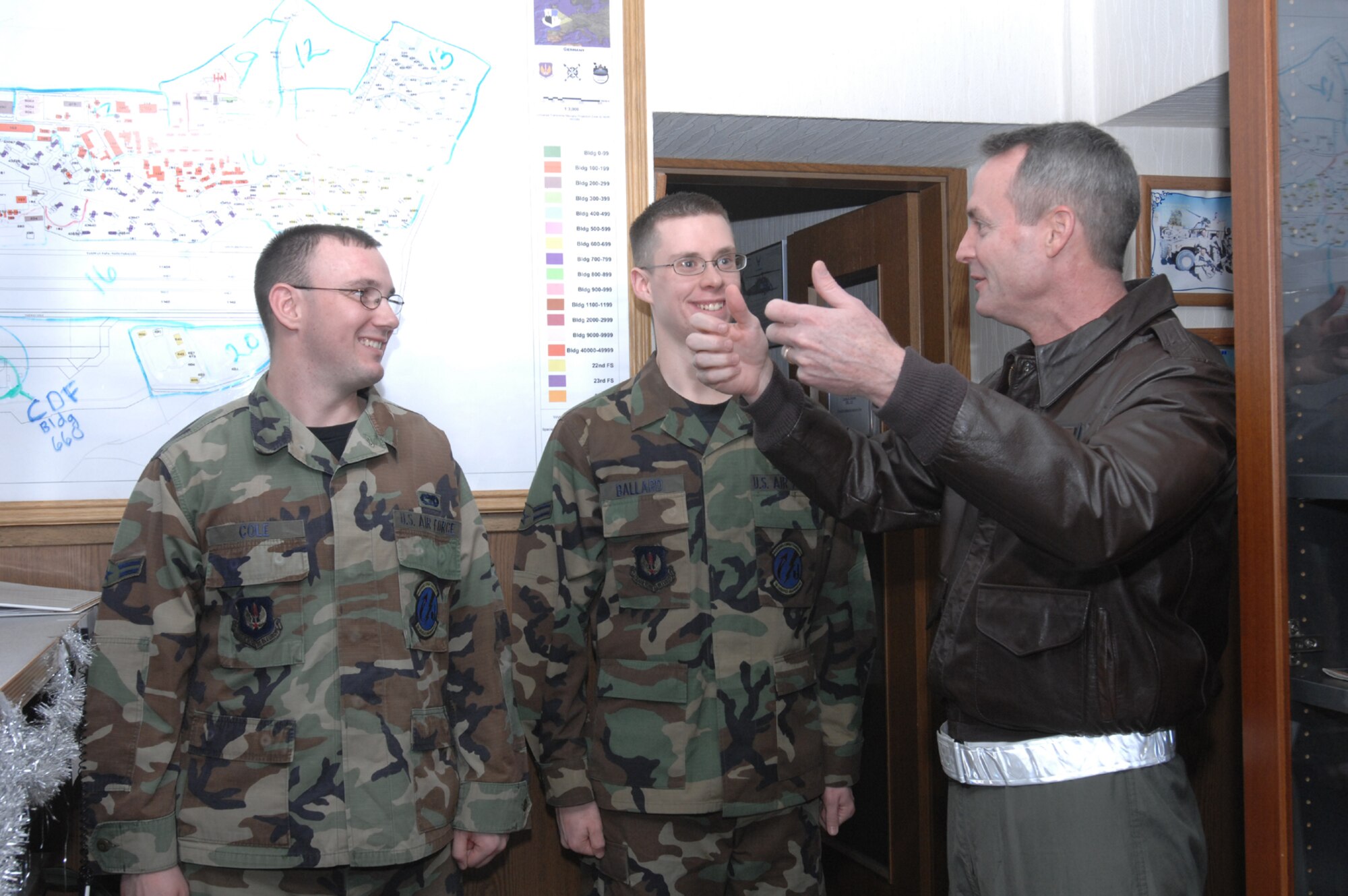 SPANGDAHLEM AIR BASE, Germany -- Airmen 1st Class Adam Cole and Johnathan Ballard look on Col. Darryl Roberson, 52nd FW commander, speaks at vehicle dispatch about the importance of truly displaying the core value of ‘Excellence in All We Do’ and how the Airman receiving coins had exemplified just that Dec. 21, 2007.  (U.S. Air Force photo/Airman 1st Class Jenifer Calhoun)
