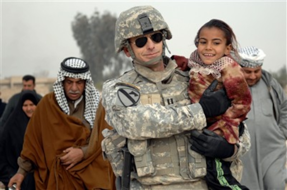 U.S. Army Capt. Keith Koppenhaver carries a young Iraqi girl suffering from a chest tumor to the Taji Sports Complex for medical attention during a combined medical effort held in Taji, Iraq, on Jan. 1, 2008.  Koppenhaver is attached to Alpha Company, 492nd Civil Affairs Battalion, attached to 1st Brigade Combat Team, 1st Cavalry Division.  