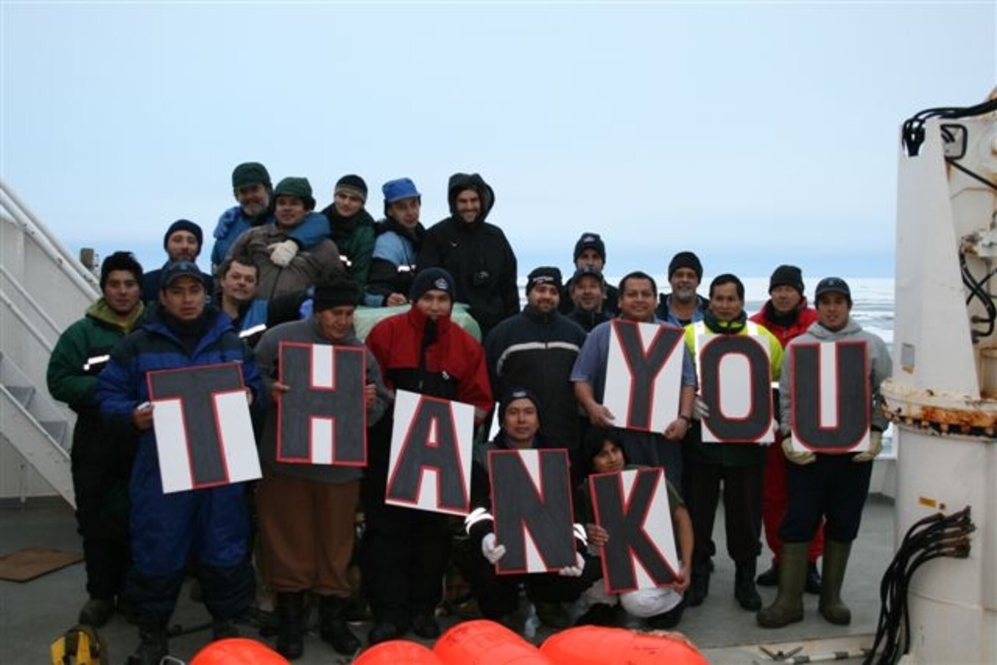 A grateful crew of the Argos Georgia show their appreciation to the crew of the C-17 after the air drop.  The Argos Georgia had suffered serious engine failure from negotiating ice while heading South in the Ross Sea, leaving it without propulsion and drifting with the ice.  The owning company, Argos Georgia Limited, researched potential options to get the needed engine parts to the stranded crew. (Courtesy photo from Argos Georgia, Ltd.)